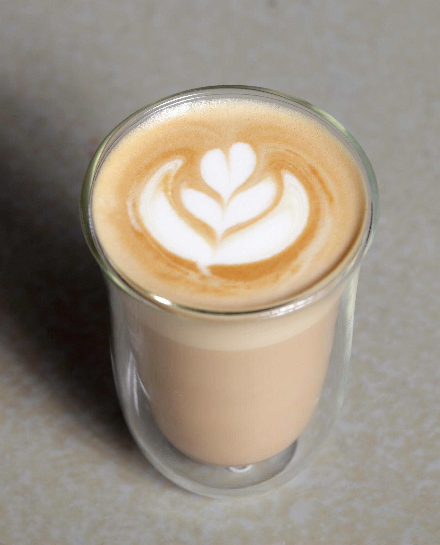 Un vaso de latte con un diseño de espuma en forma de corazón encima.