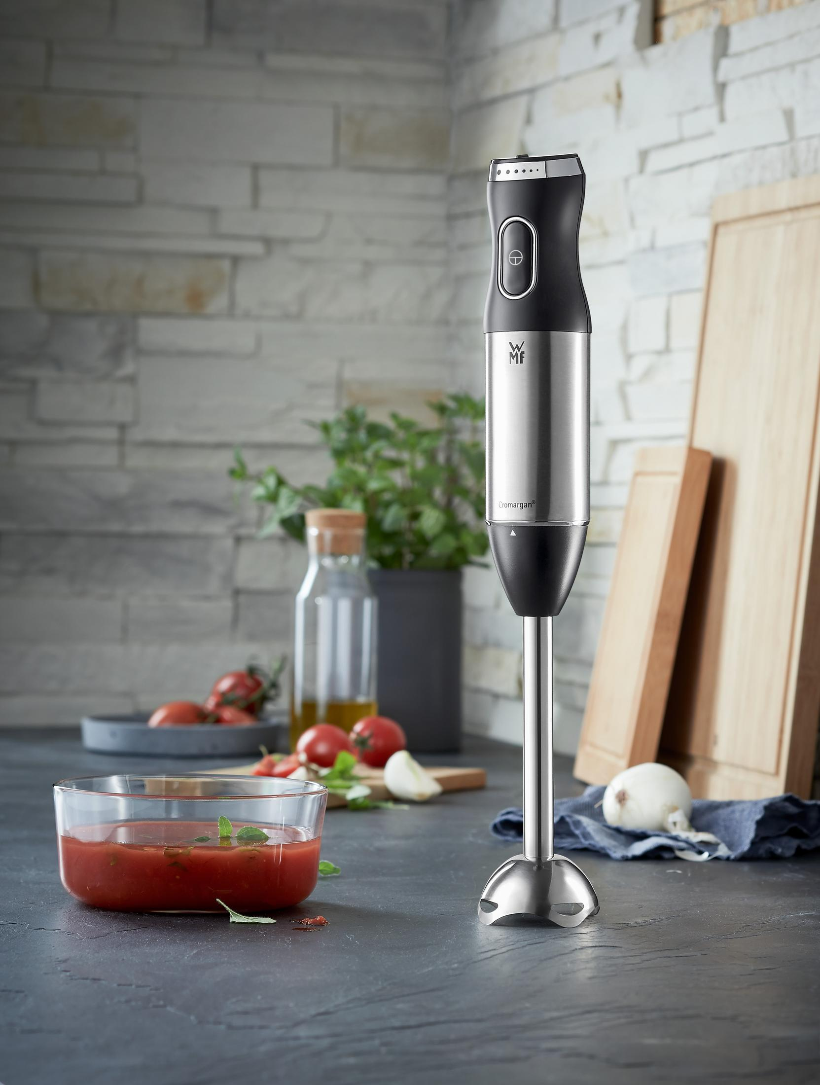 Ein Edelstahl-Stabmixer mit Zutaten auf dem Tisch.