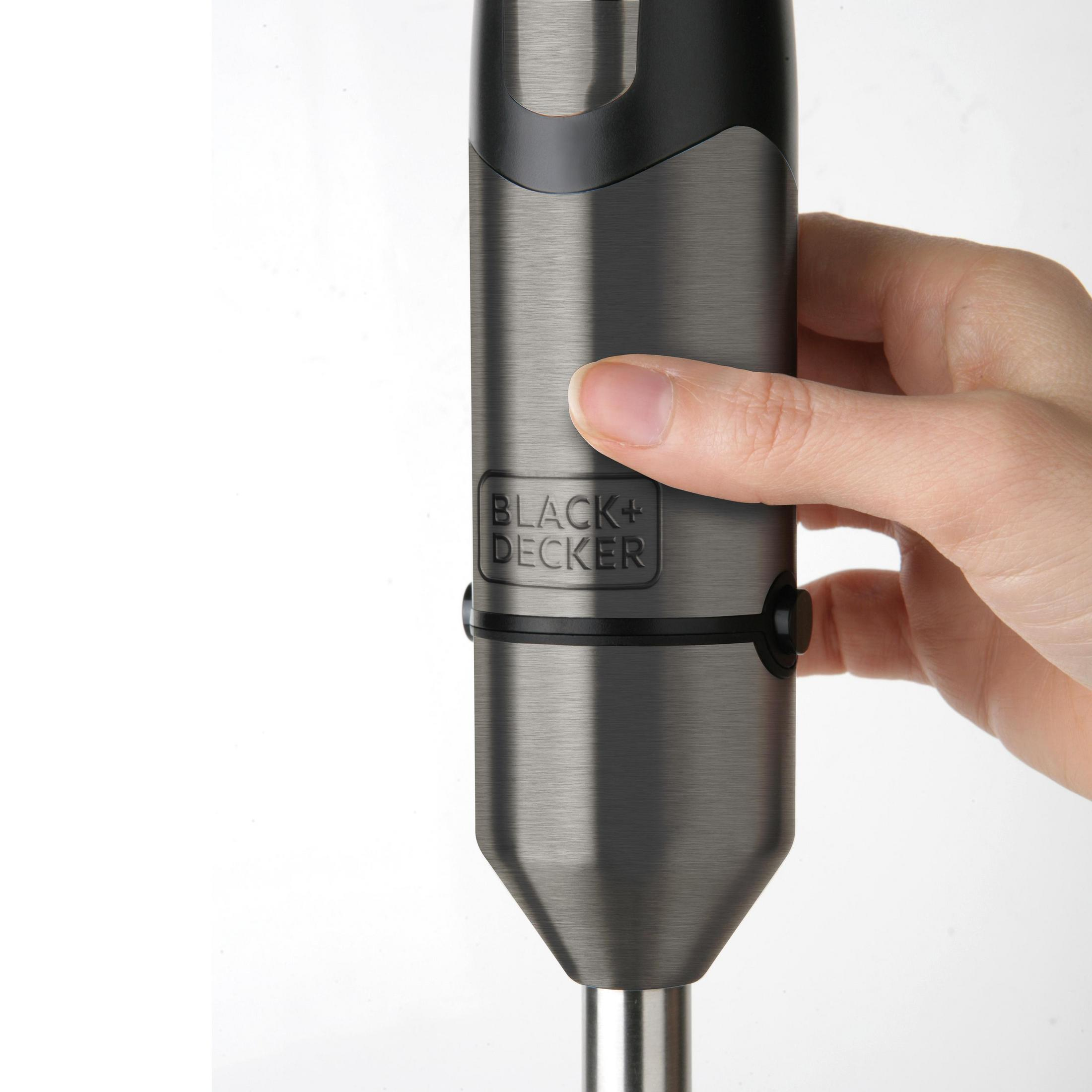 Mano che tiene un frullatore a immersione nero e grigio. Il marchio è Black+Decker.