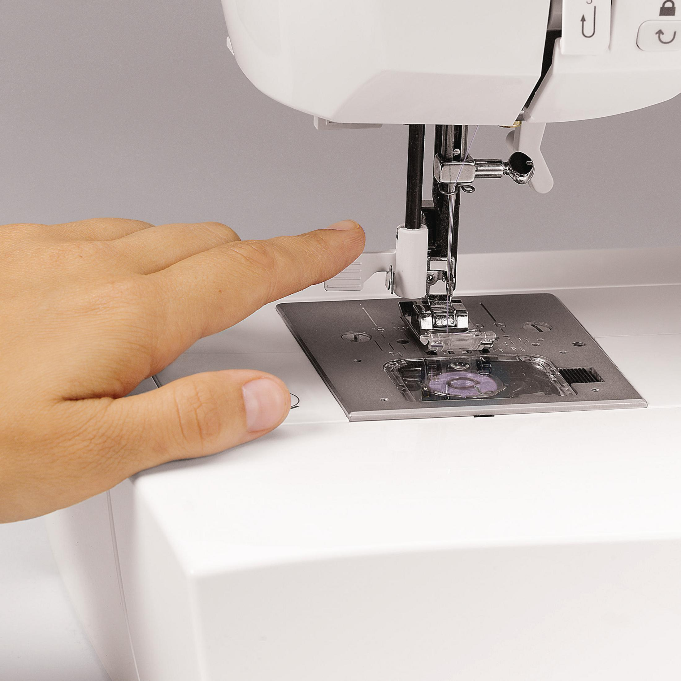Eine Hand ist in der Nähe von Nadel und Platte einer Nähmaschine. Nahaufnahme einer Nähmaschine in Betrieb.