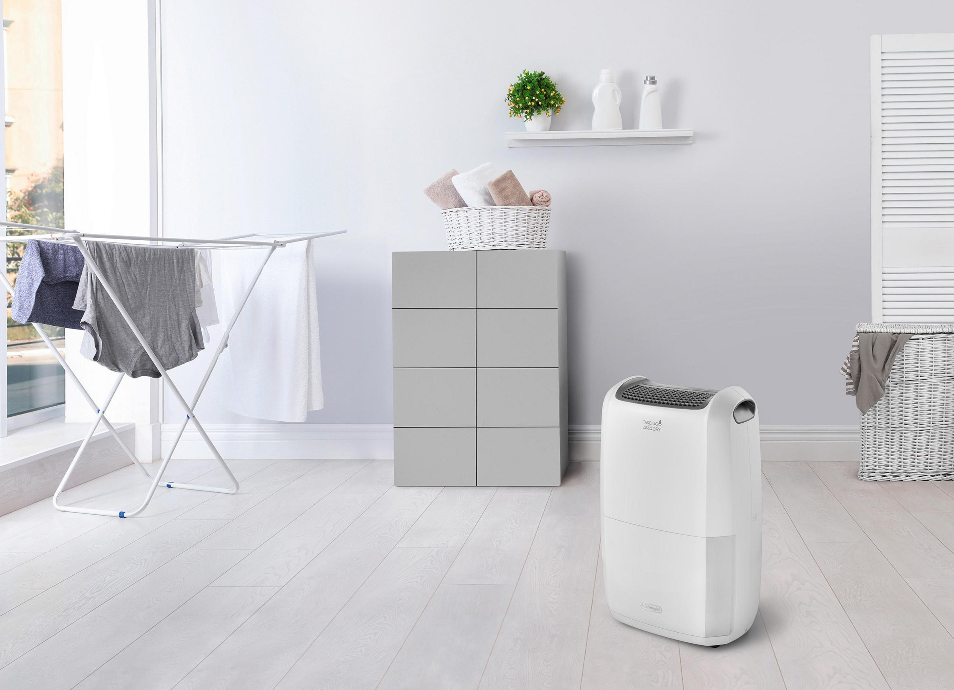 Jasny pokój z suszarką na ubrania, białą szafką i osuszaczem. Biała podłoga.