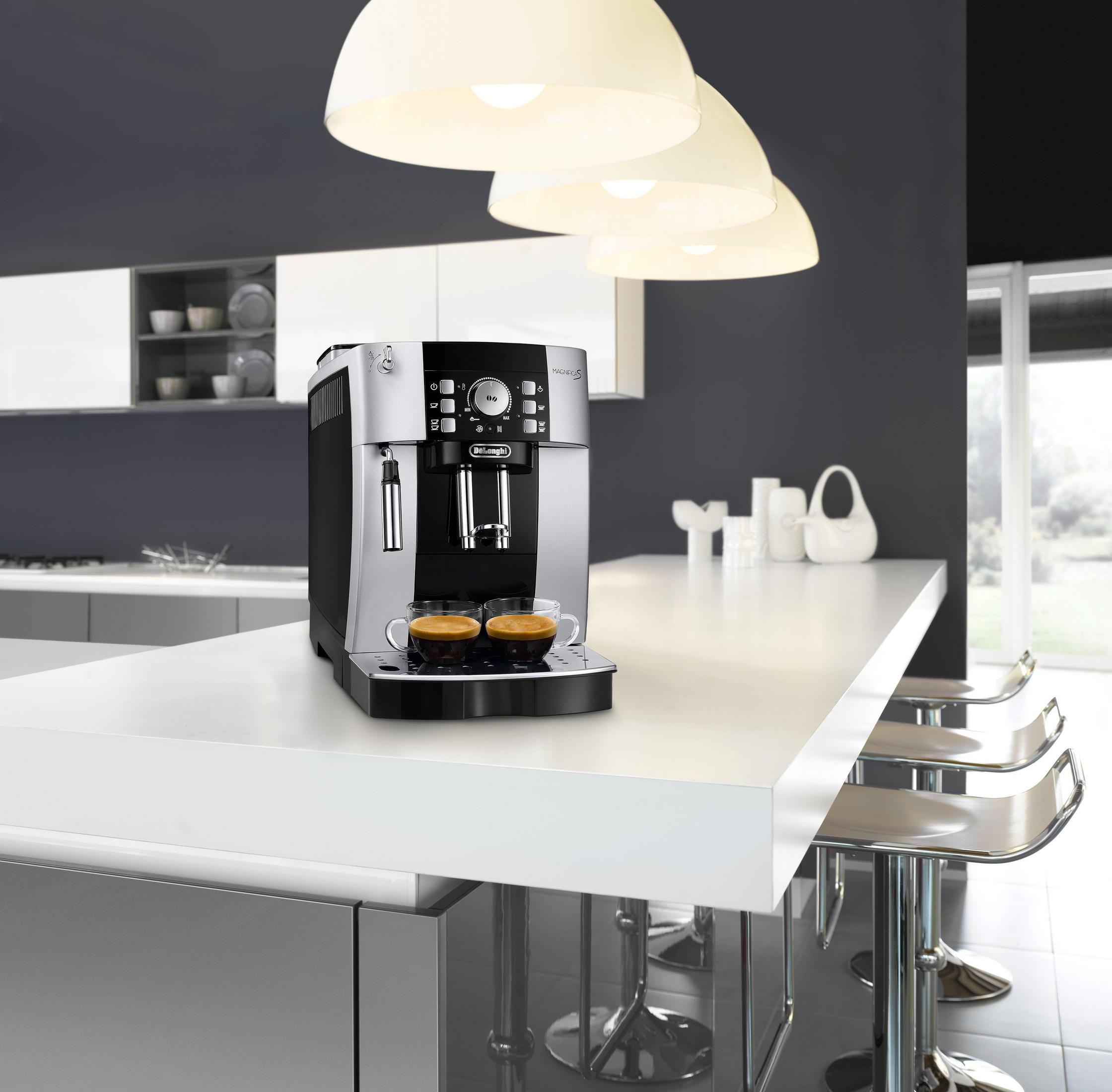 Srebrno-czarny ekspres do kawy DeLonghi na białym blacie z dwiema filiżankami kawy.