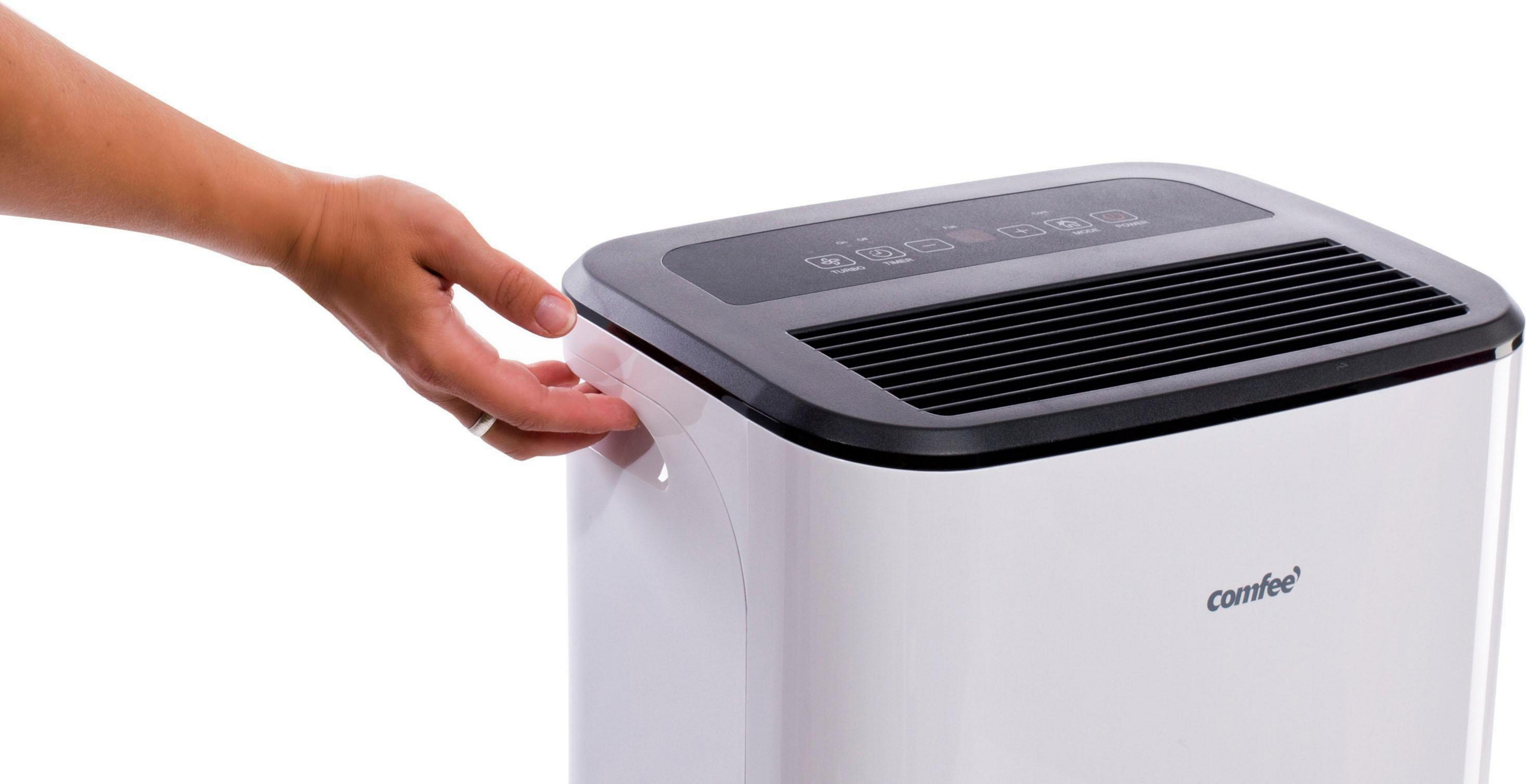 Ręka sięgająca po biało-czarny osuszacz powietrza Comfee.