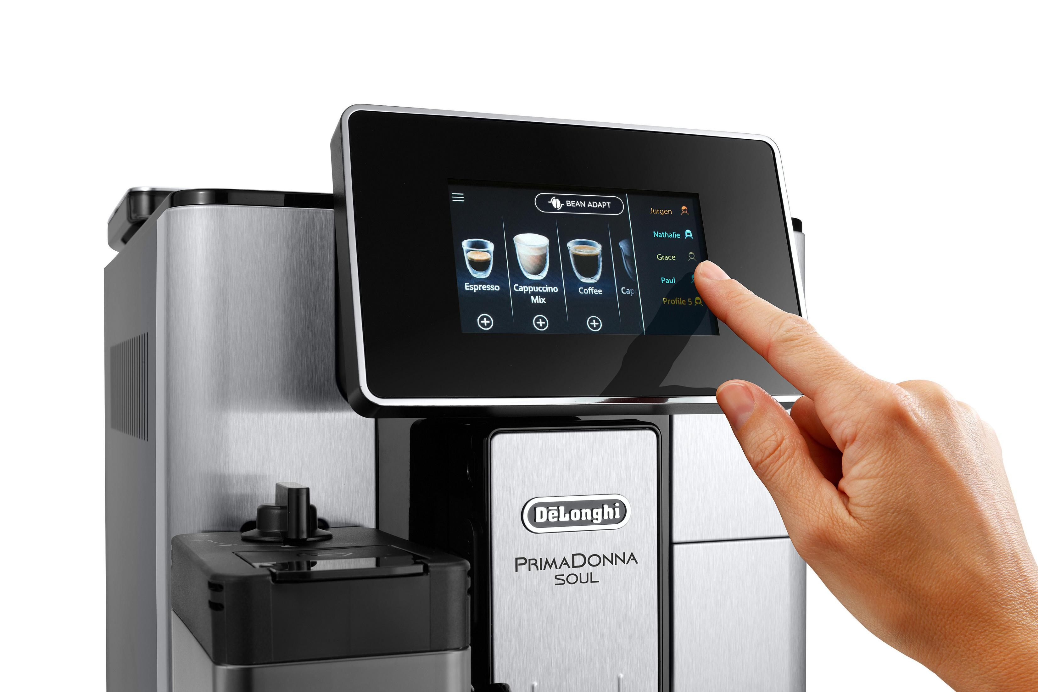 Der Finger einer Person zeigt auf einen Touchscreen einer Kaffeemaschine. Der Bildschirm zeigt Kaffeeoptionen an.