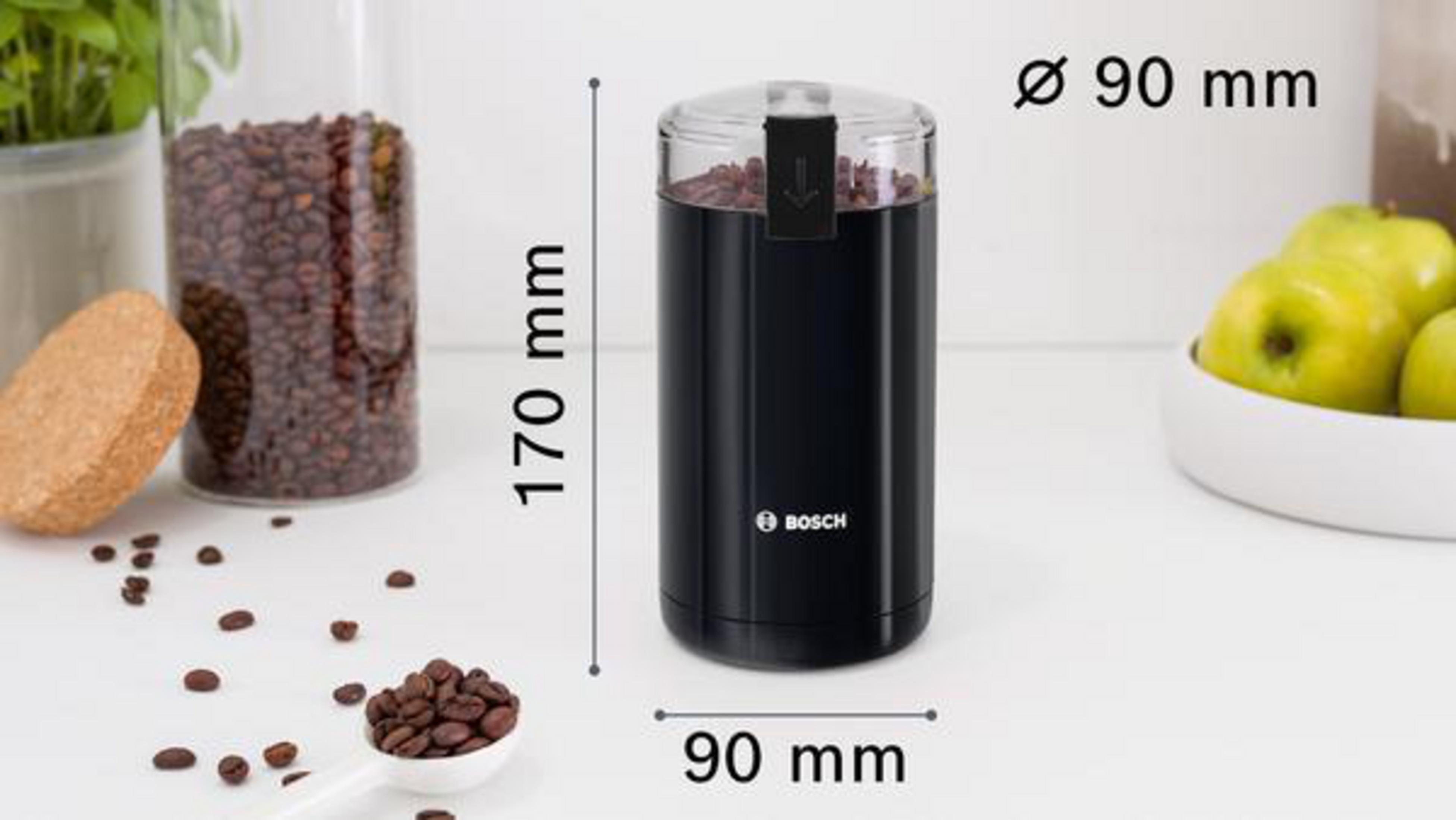 Black coffee grinder with beans and a spoon, with text, and dimension marks on a white surface.
