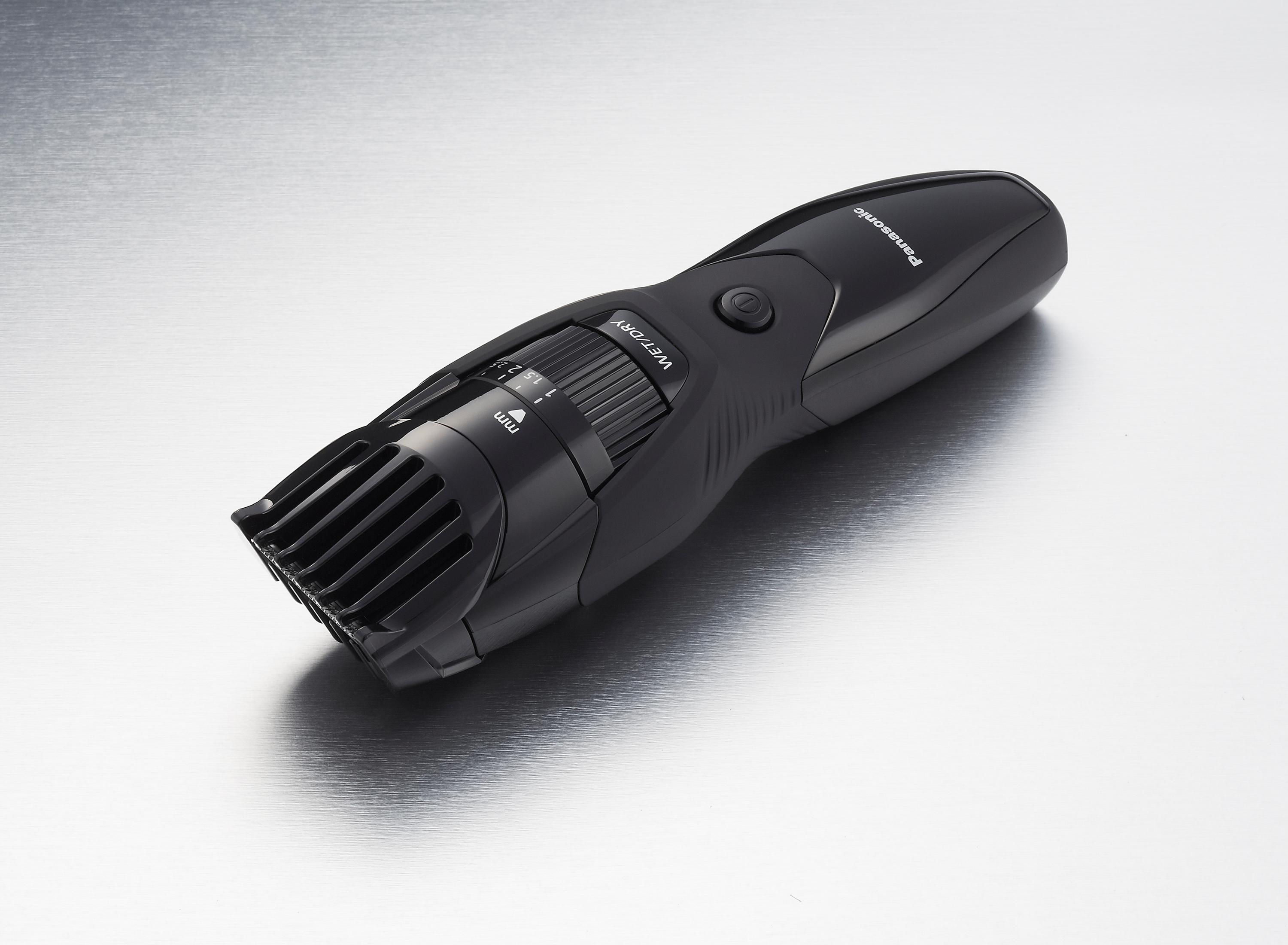 Une tondeuse à barbe noire sur une surface argentée. La tondeuse a un cadran et la marque 'Panasonic'.
