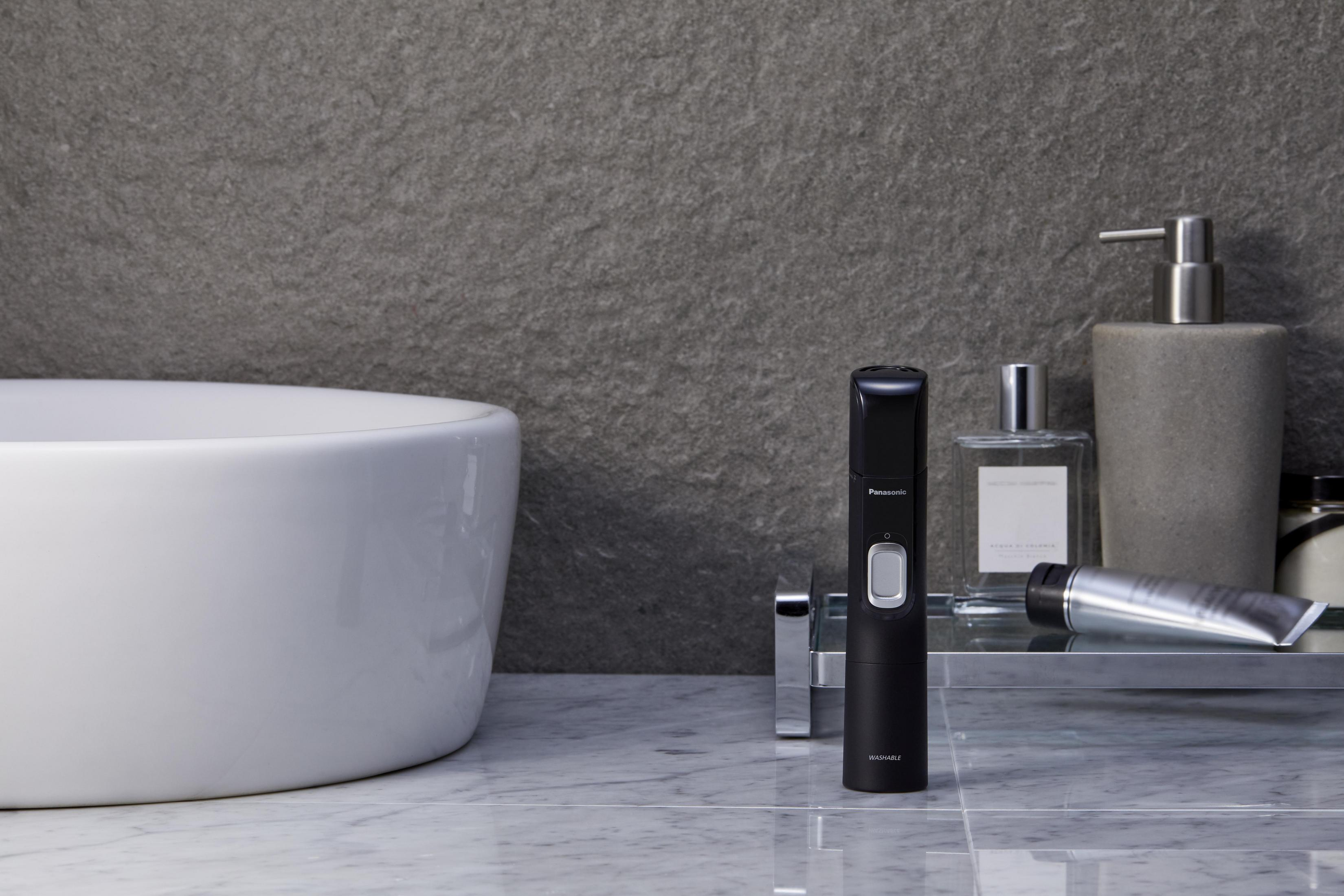 Schwarzer Trimmer, Toilettenartikel und ein weißes Waschbecken im Badezimmer.
