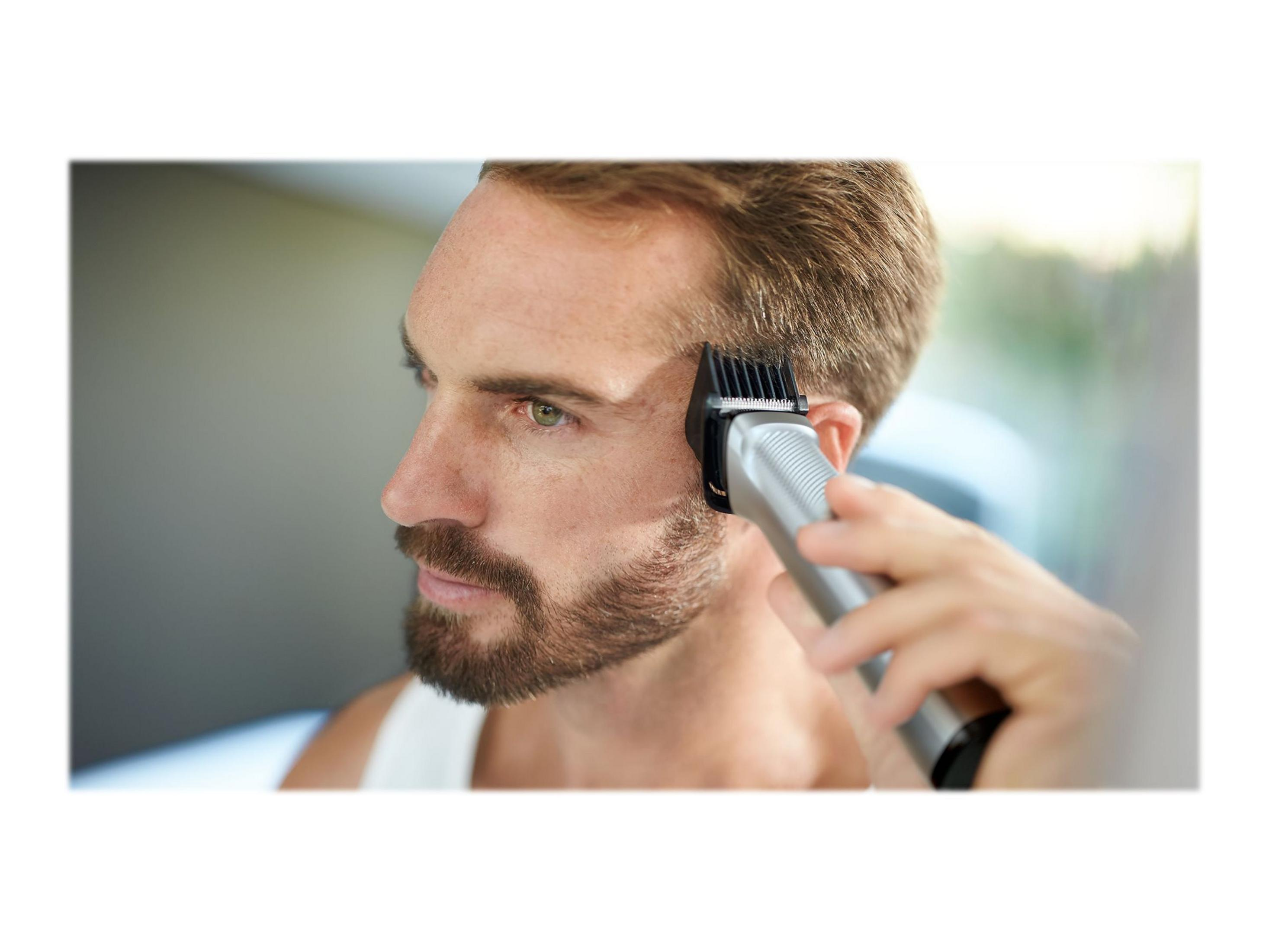 Uomo usa un tagliacapelli per tagliare i capelli. Messa a fuoco sul tagliacapelli e sui capelli.