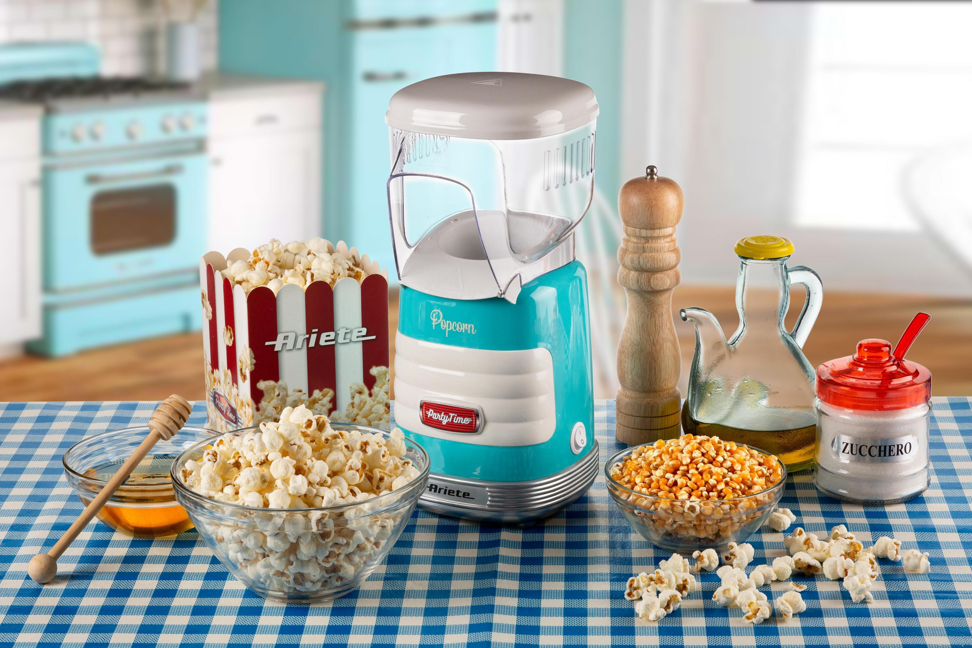 Stół z popcornem, maszyną do popcornu, miodem, olejem i cukrem, z niebieską kratkowaną serwetą.