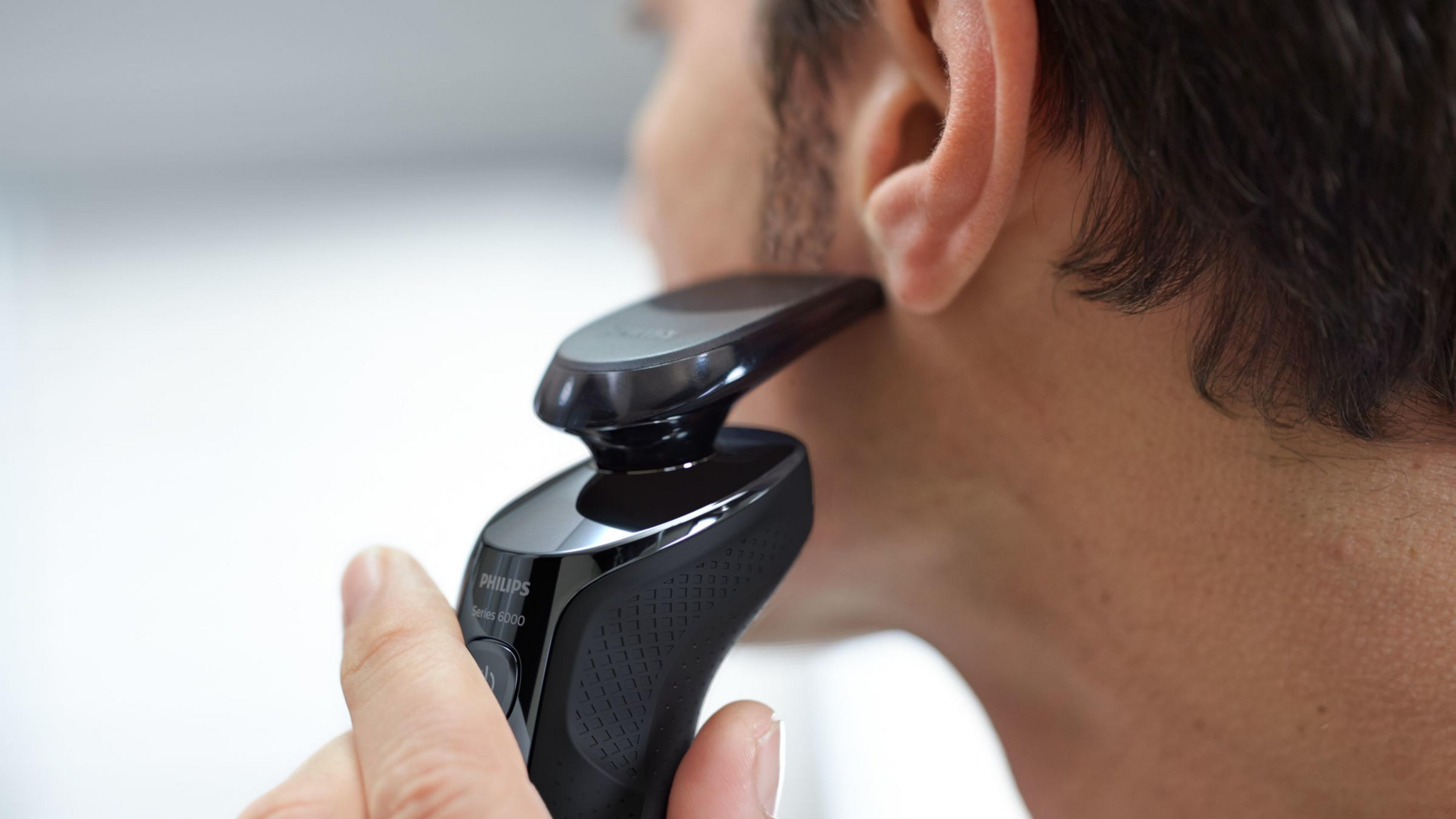 Uomo che si rade con un rasoio elettrico Philips Serie 5000.