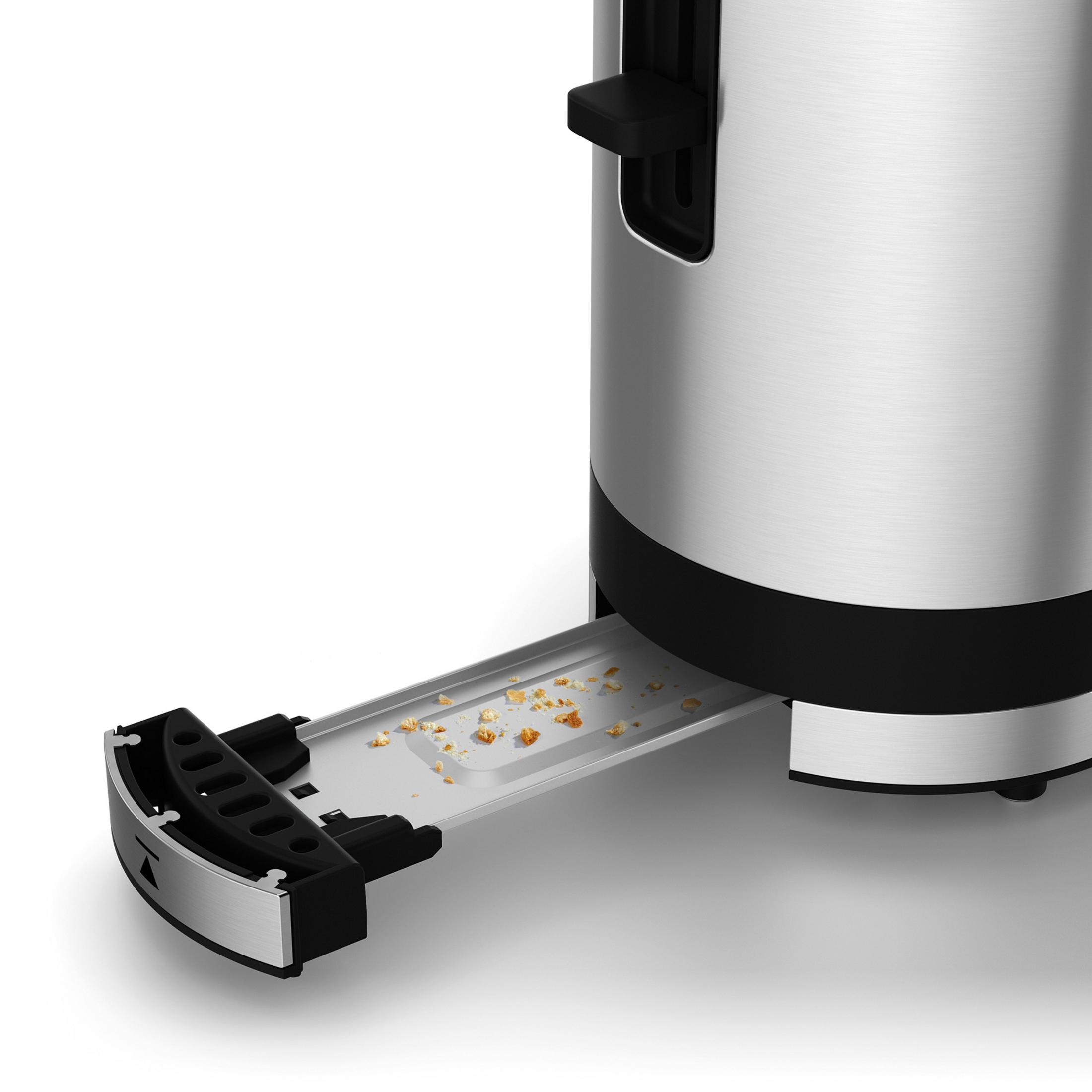 Metalowy toster z wysuniętą tacką na okruchy, pokazującą okruchy chleba. Jest na białej powierzchni.