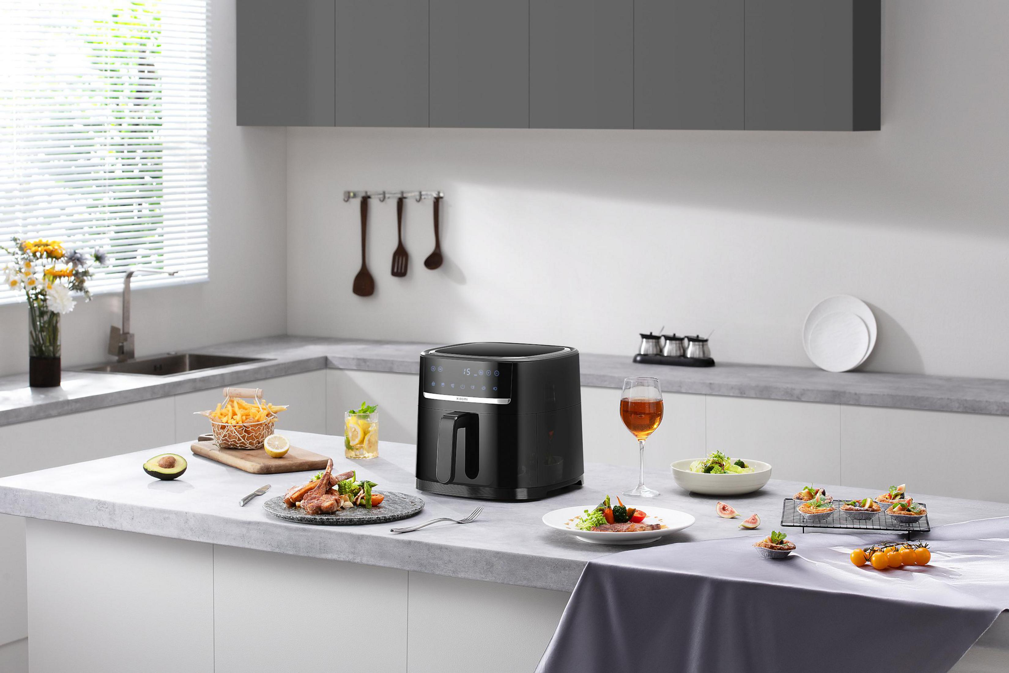 Scena kuchenna: frytownica, jedzenie, napoje i składniki na blacie.