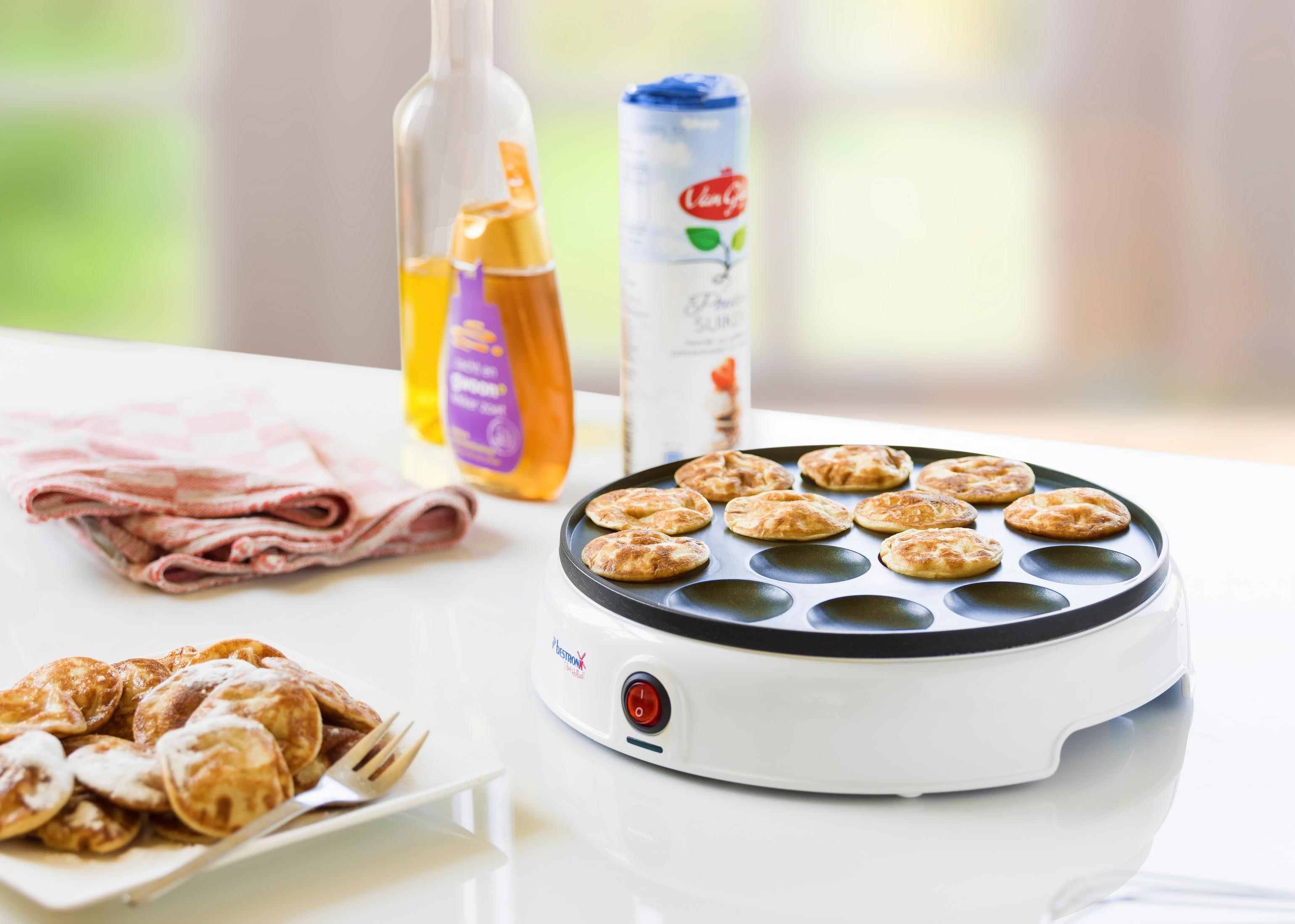 Naleśnikarka z naleśnikami. Widoczne butelki i pojemnik.