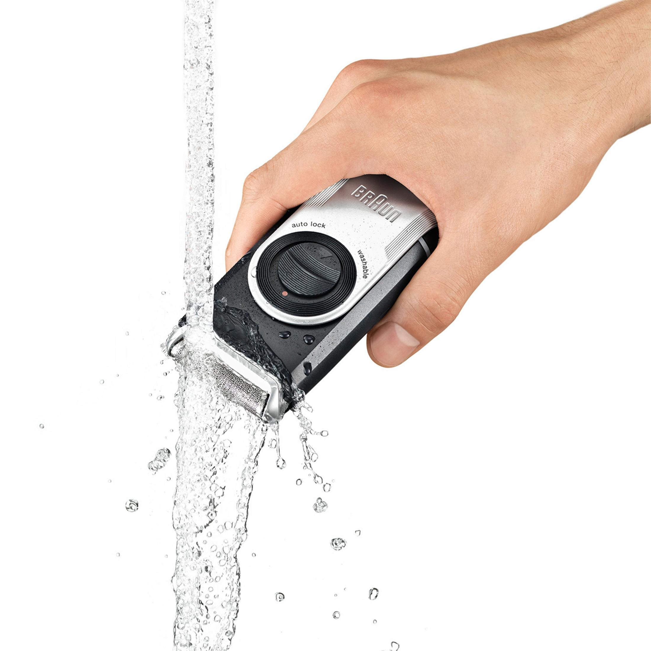 Una mano che tiene un rasoio nero e argento sotto un getto d'acqua.