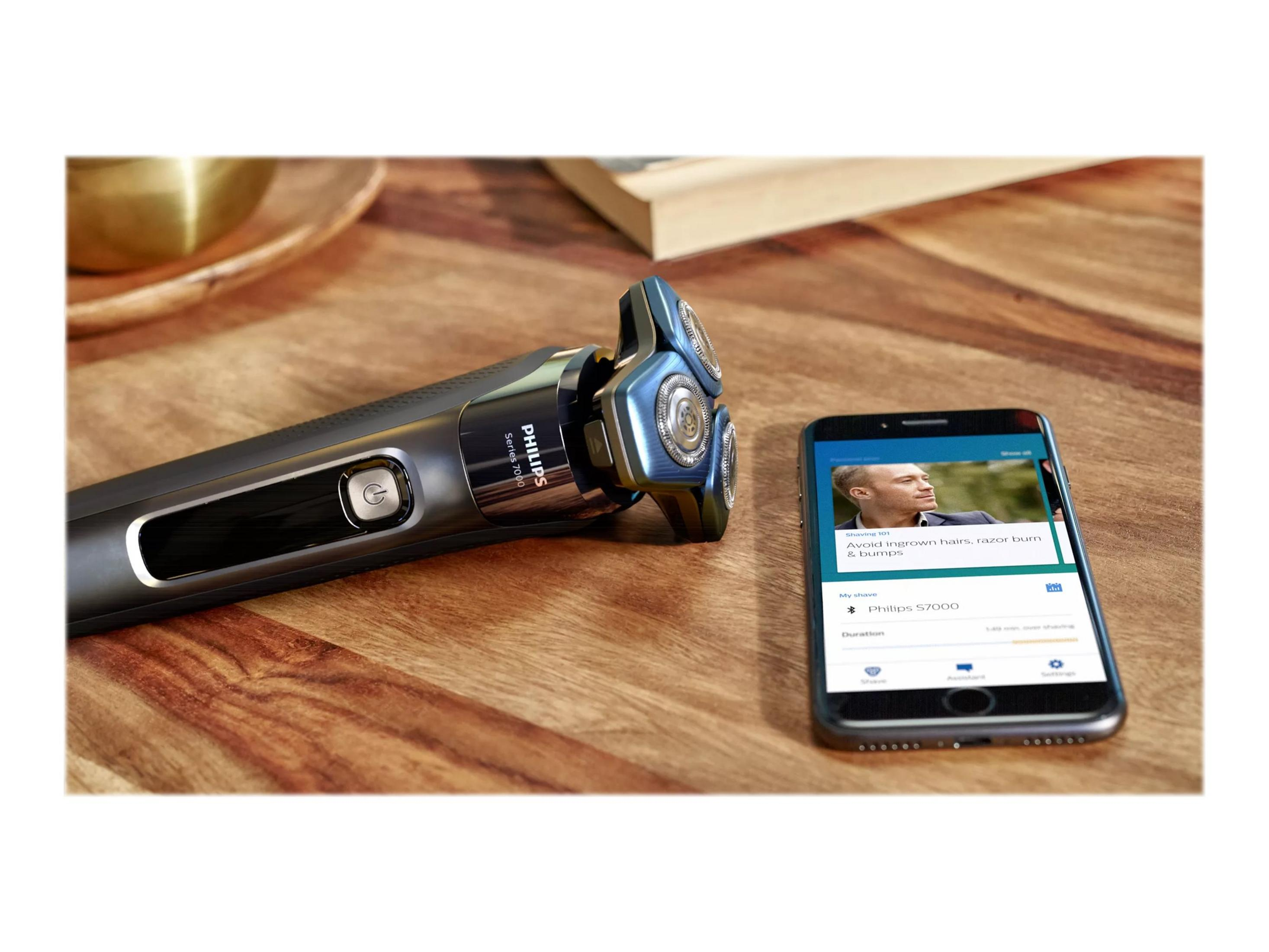 Un rasoio con un telefono che mostra consigli per la rasatura su un tavolo di legno.