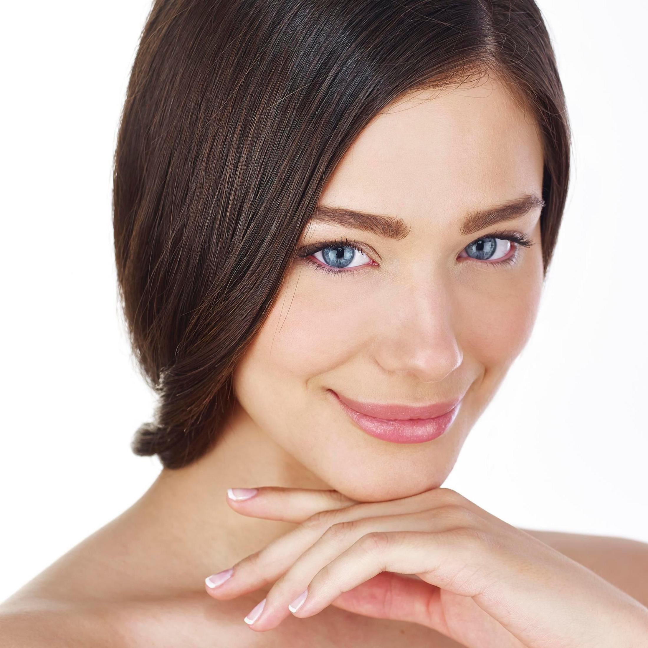 Kobieta z niebieskimi oczami uśmiecha się. Ręka pod brodą. Białe tło.