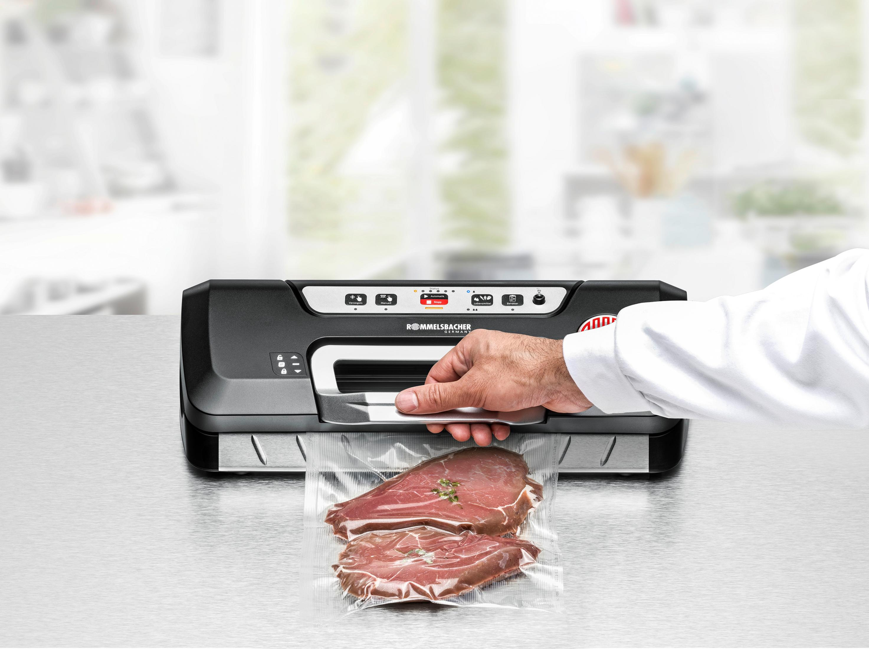 Osoba zamykająca mięso w zgrzewarce próżniowej. Czarna maszyna, przezroczysta torba z dwoma kawałkami mięsa.