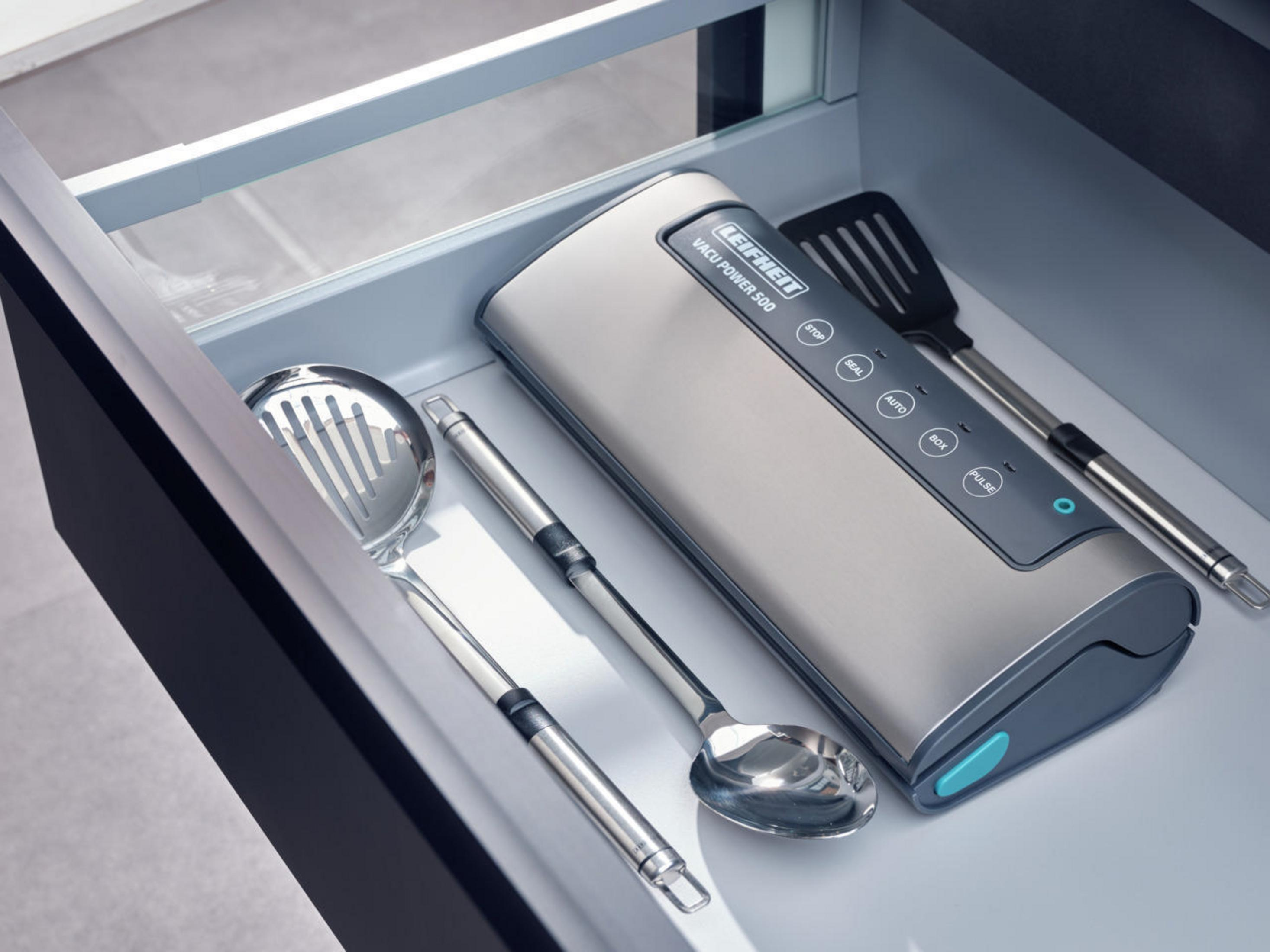 Zgrzewarka próżniowa Leifheit w szufladzie z innymi przyborami. Srebrny i szary schemat kolorów.