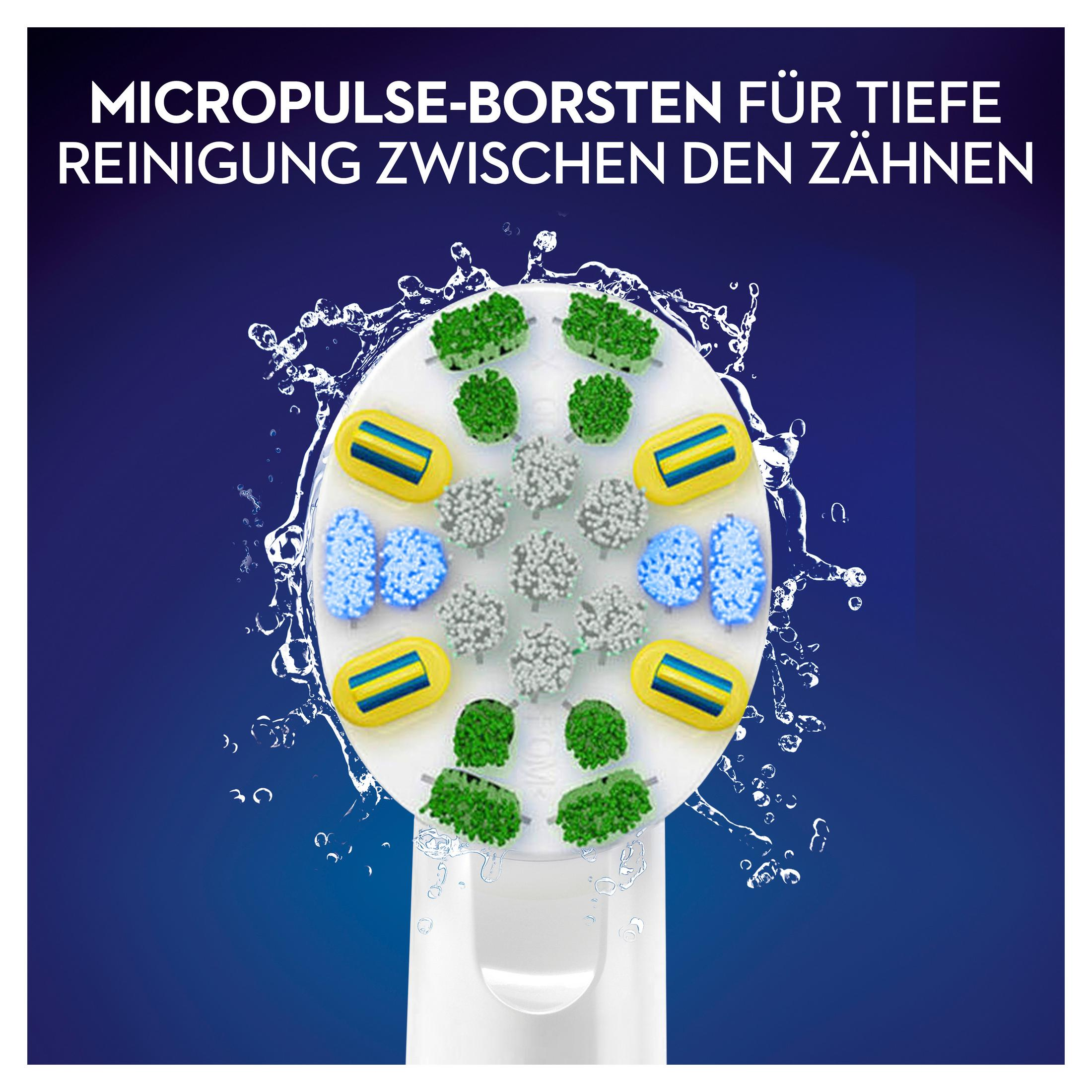 Nahaufnahme eines weißen Zahnbürstenkopfes mit blauen, grünen und gelben Borsten und Wassertropfen.