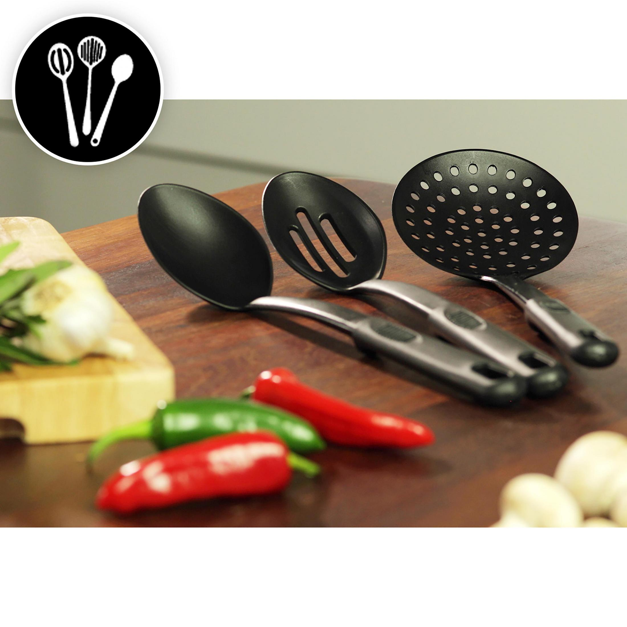 Grupa czarnych przyborów kuchennych na drewnianej powierzchni, z papryczkami chili i czosnkiem.