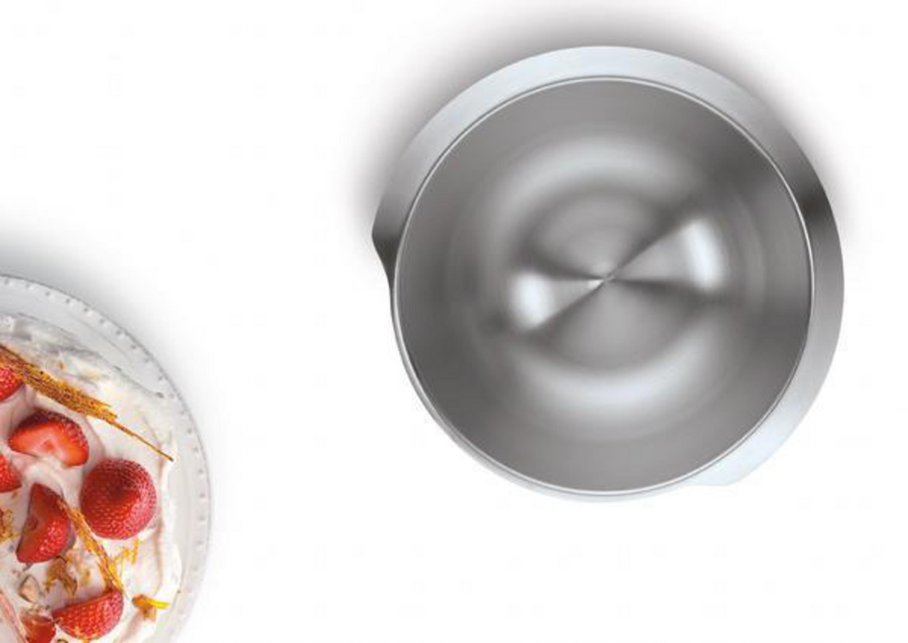 Eine Edelstahlschüssel neben einem Teller Kuchen mit Erdbeeren.