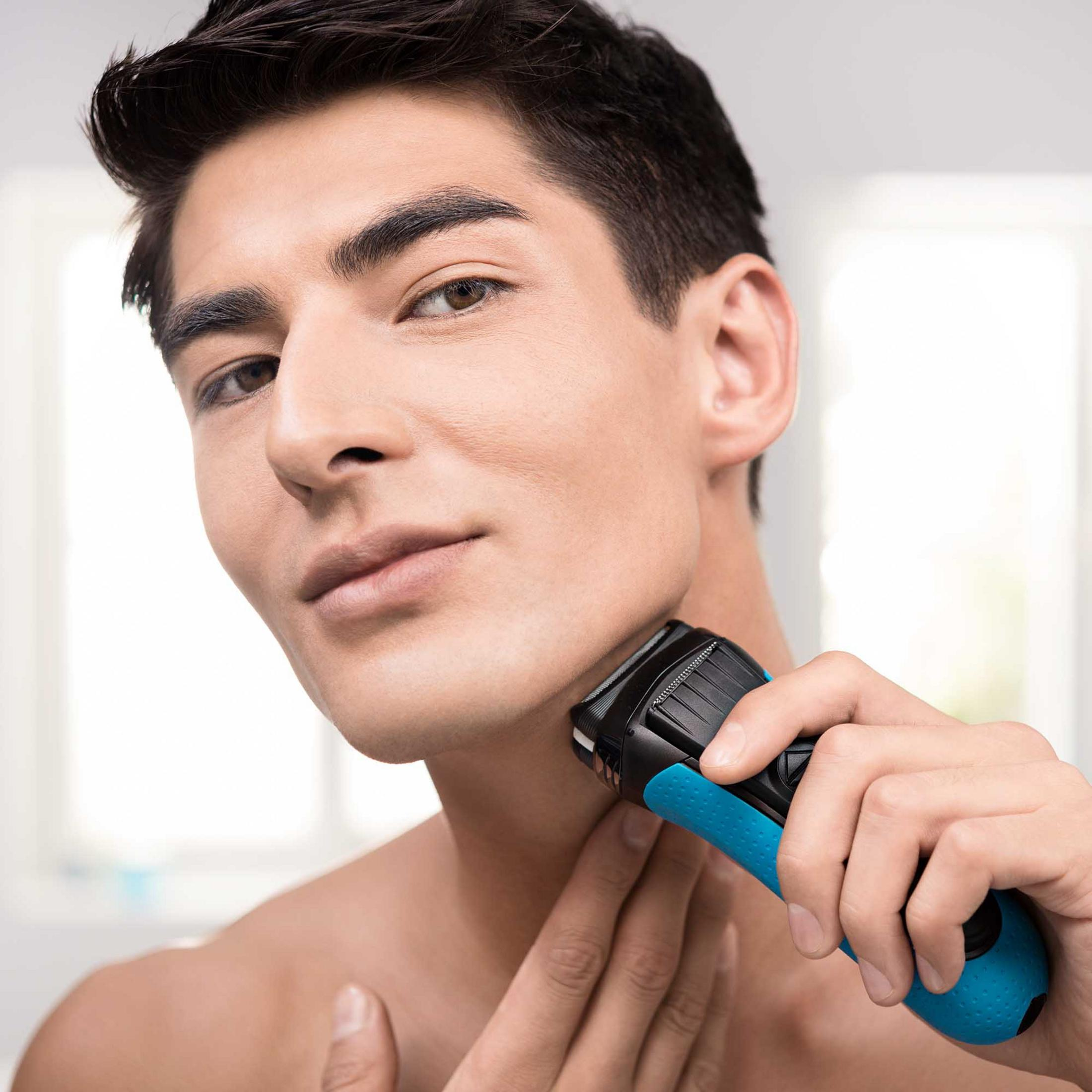 Un uomo si rade il collo con un rasoio elettrico blu e nero.