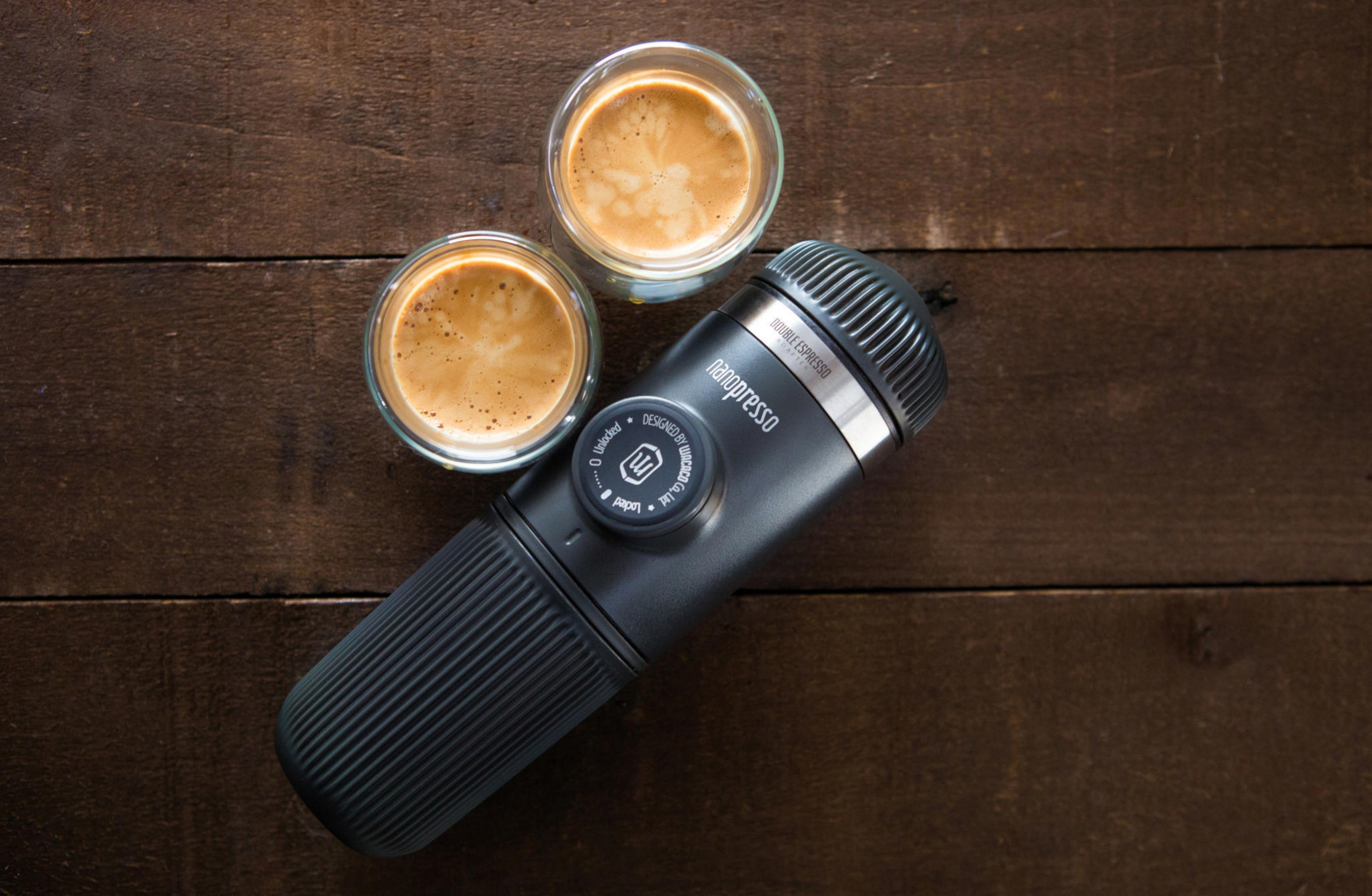Dos chupitos de espresso y una cafetera espresso portátil negra y plateada.