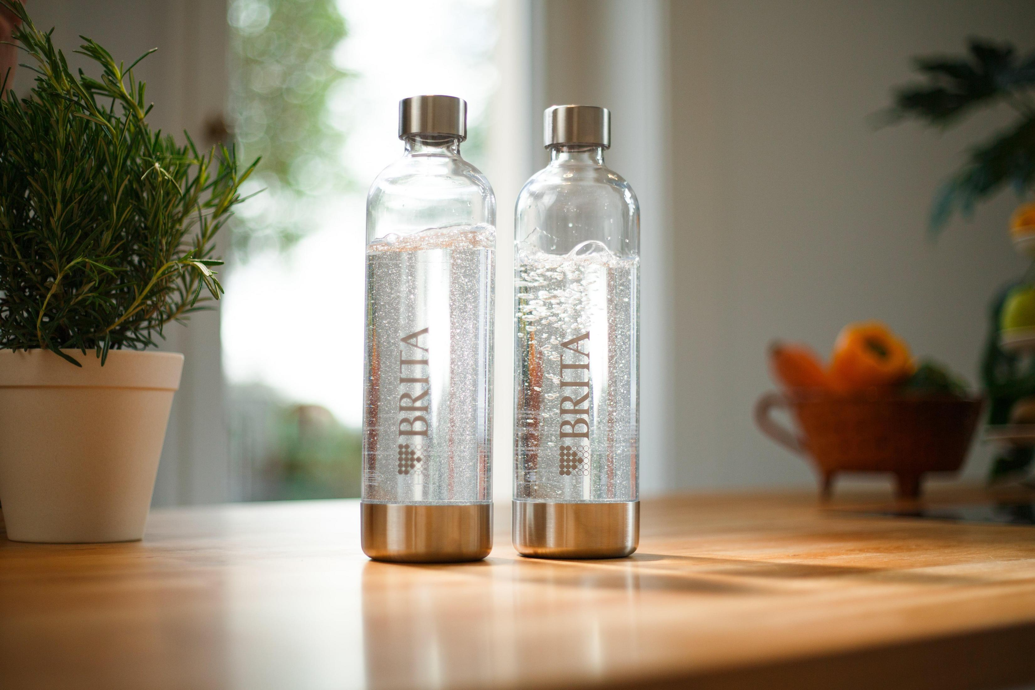 Zwei Brita-Wasserflaschen mit Wasser gefüllt auf einem Holztisch.