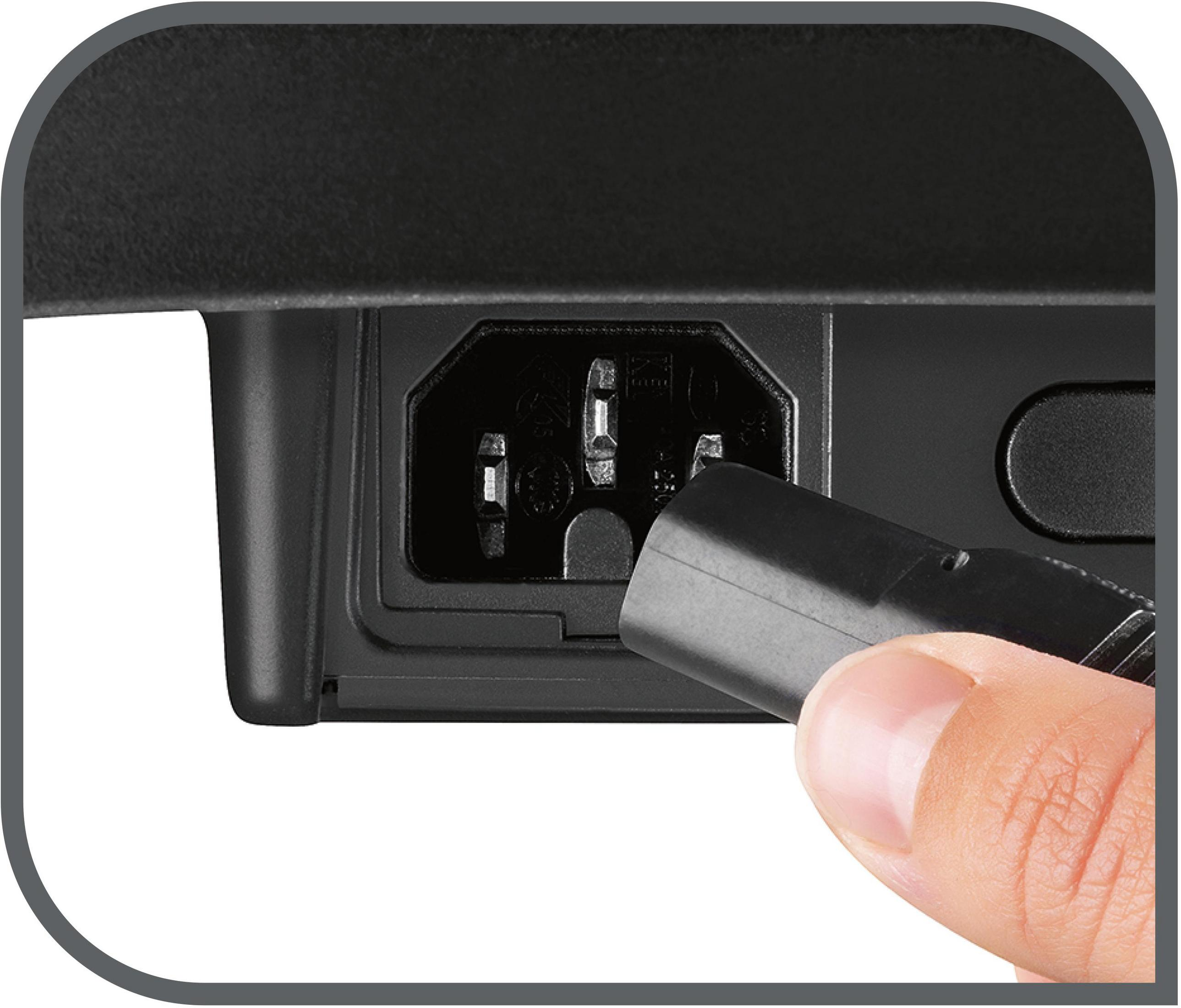 Zbliżenie czarnego złącza zasilania urządzenia z ręką wkładającą czarną wtyczkę.