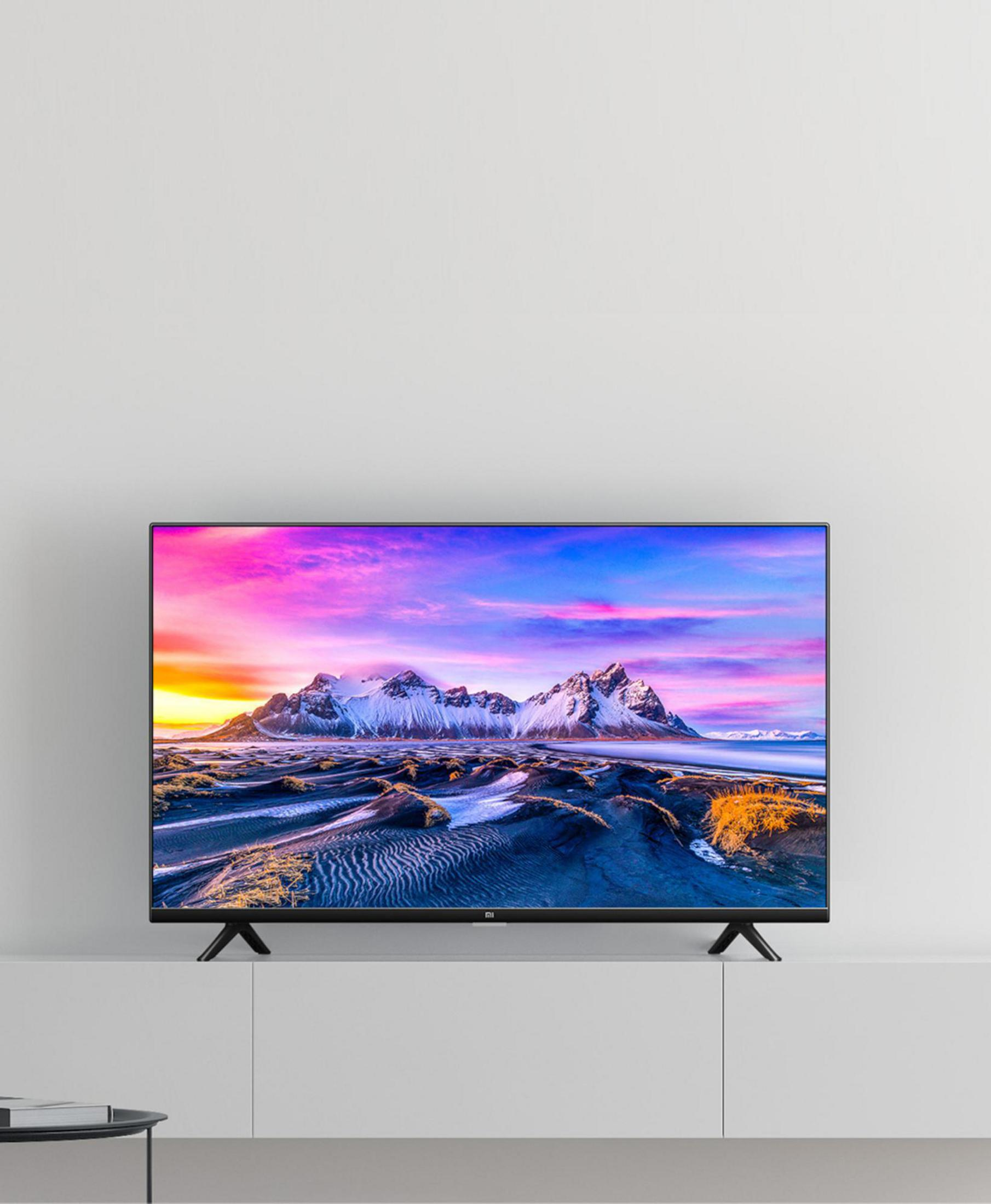 TV met een kleurrijke zonsondergang boven besneeuwde bergen. De TV staat op een witte plank.