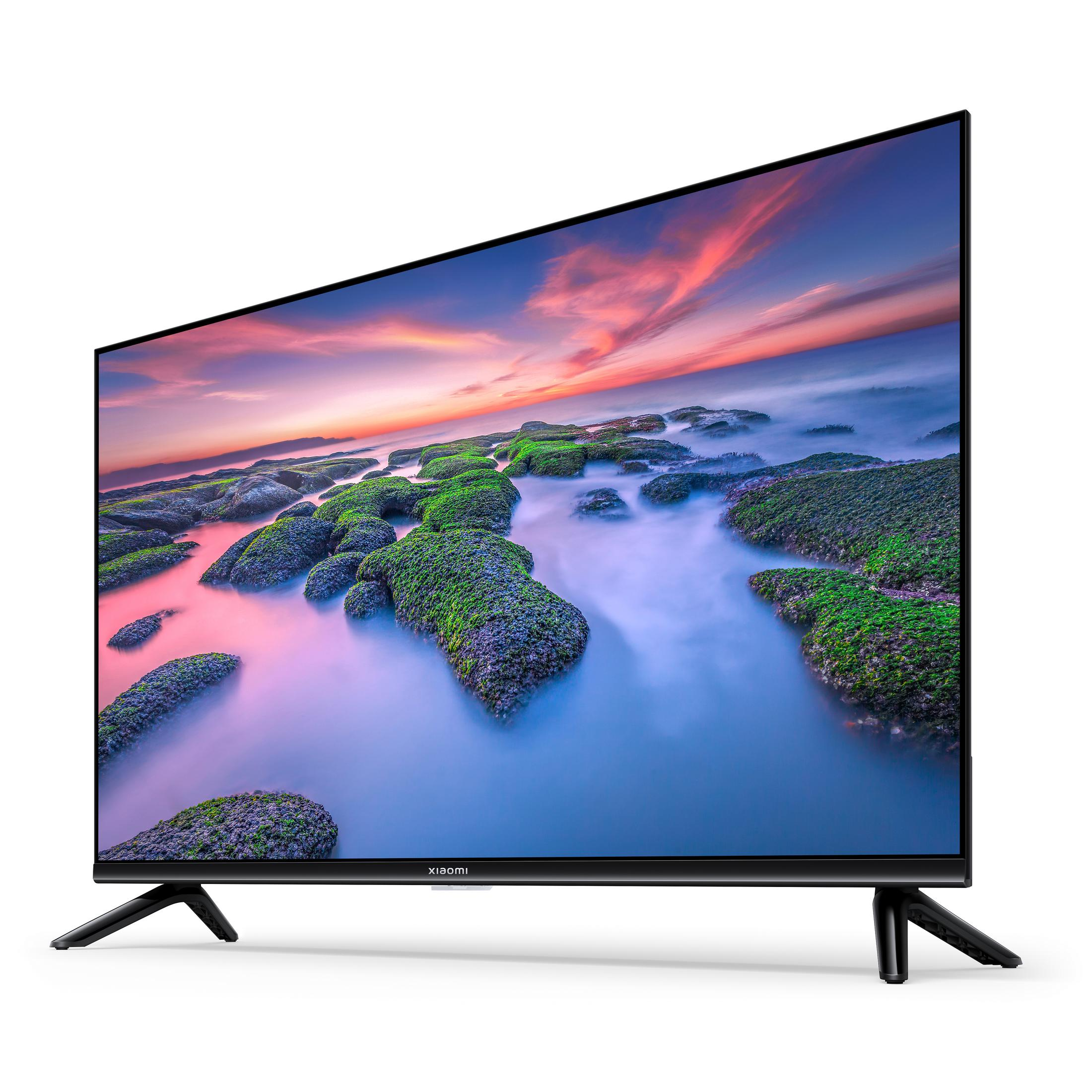 Telewizor Xiaomi wyświetla kolorowy krajobraz na białym tle, wspierany przez czarne nogi.