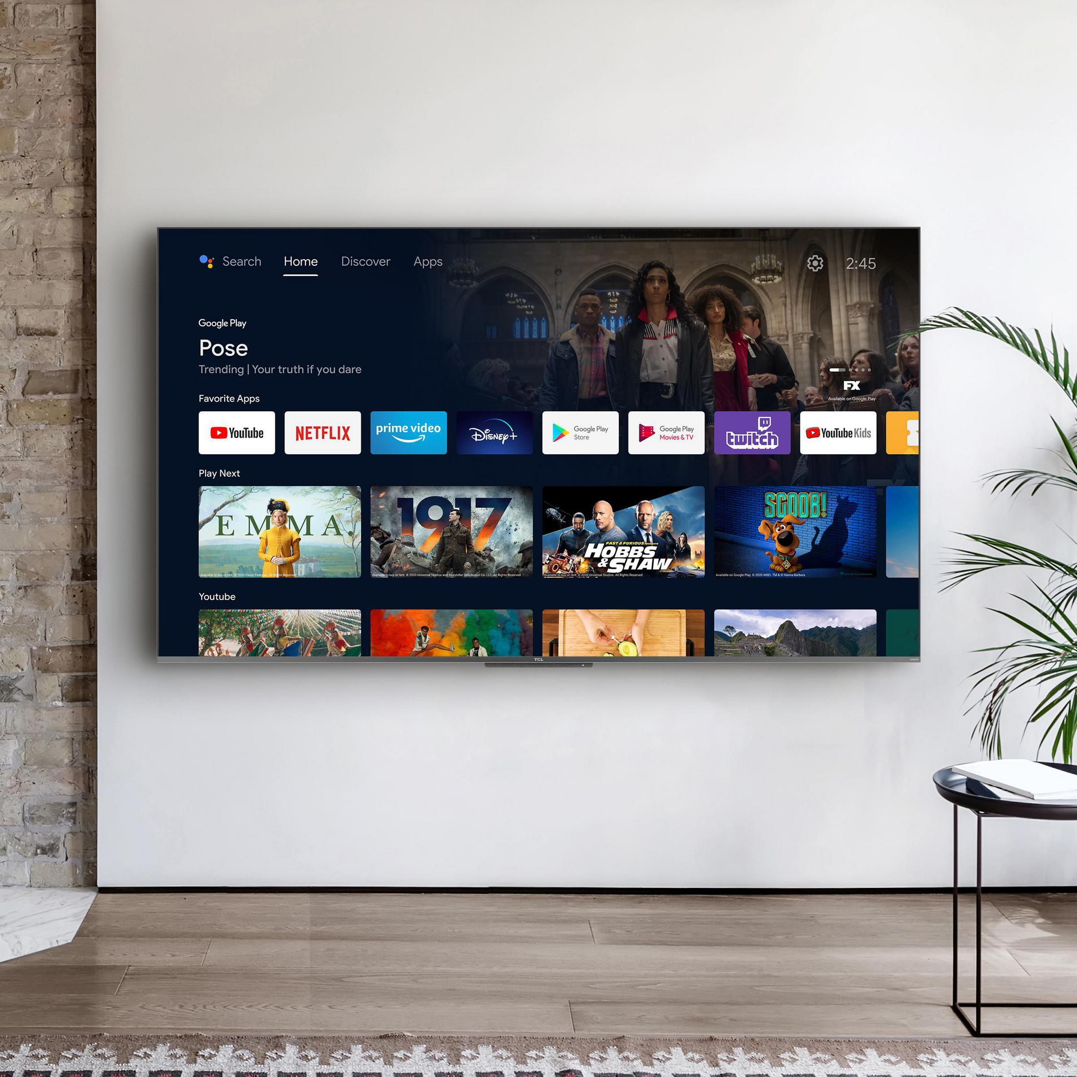 TV affichant des applications de streaming sur un mur blanc. Une plante et une table d'appoint à droite.