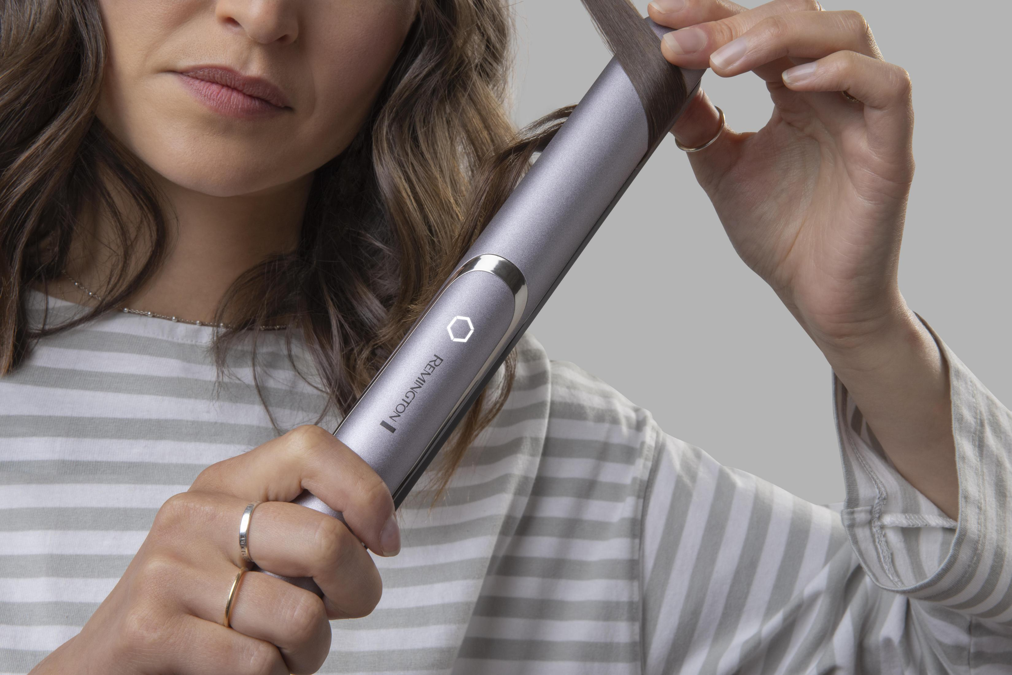 Una persona usa una piastra per capelli. Tengono il dispositivo con cura.