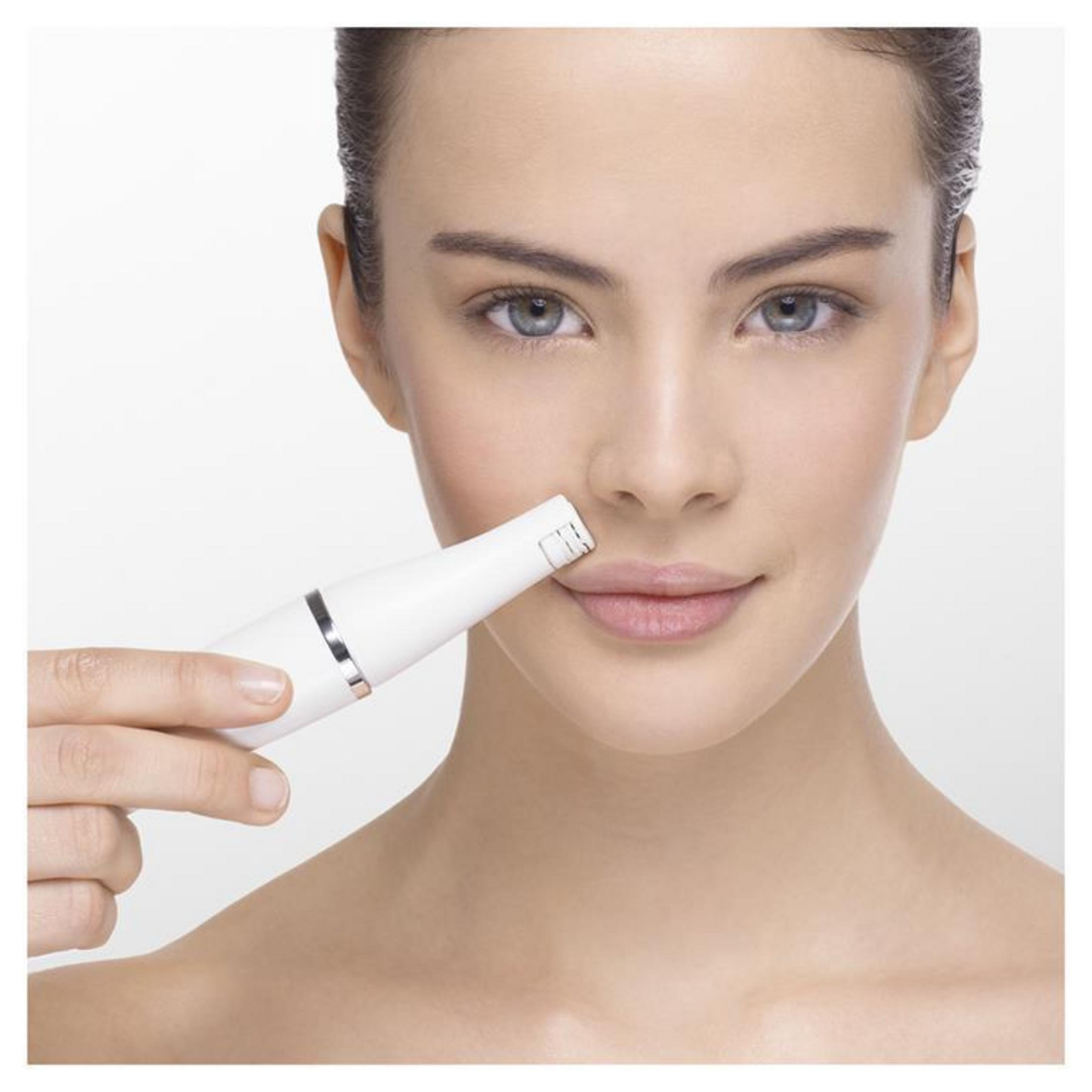 Kobieta trzymająca biały depilator w pobliżu górnej wargi, zbliżenie na twarz.