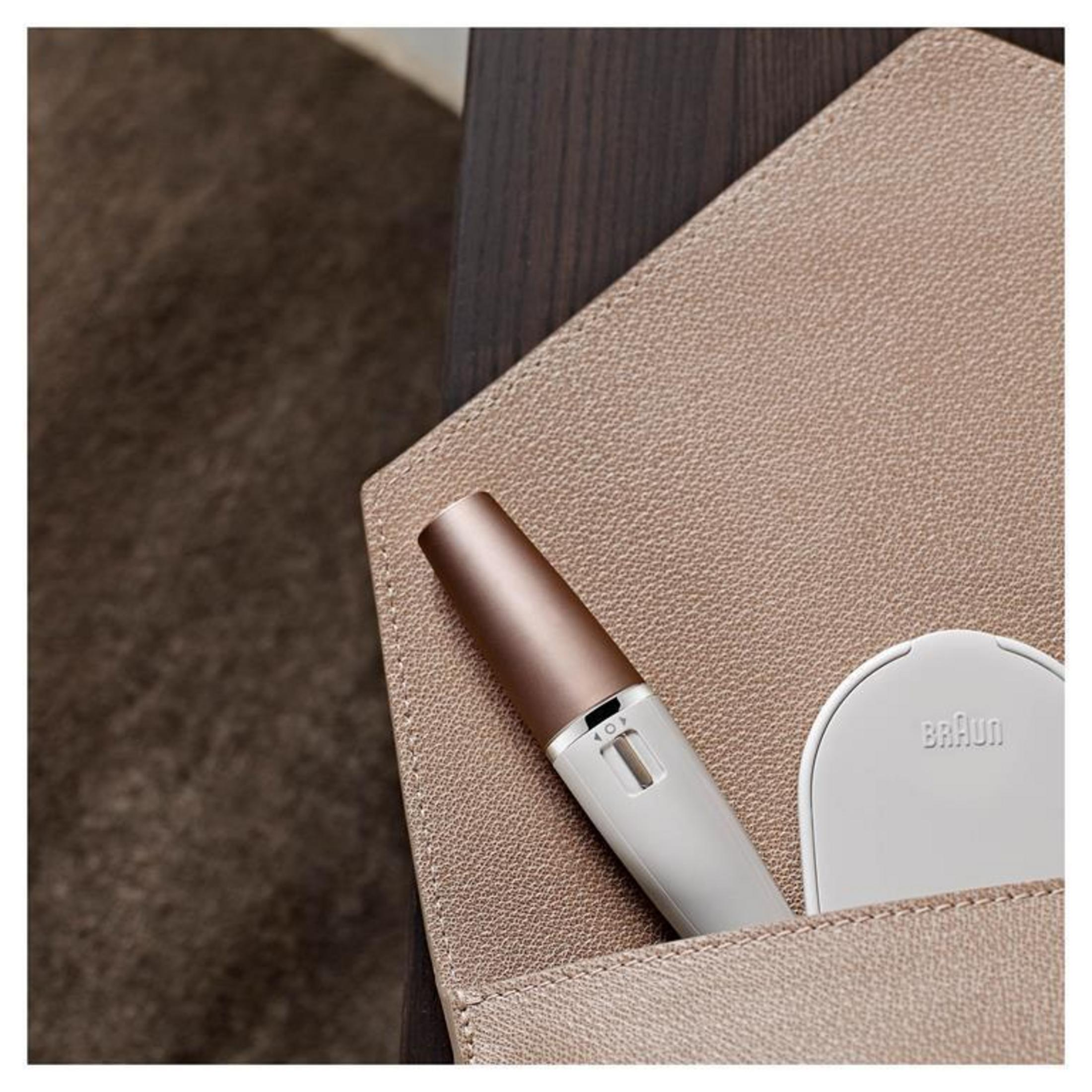 Biała i różowo-złota golarka elektryczna znajduje się w beżowym skórzanym etui.