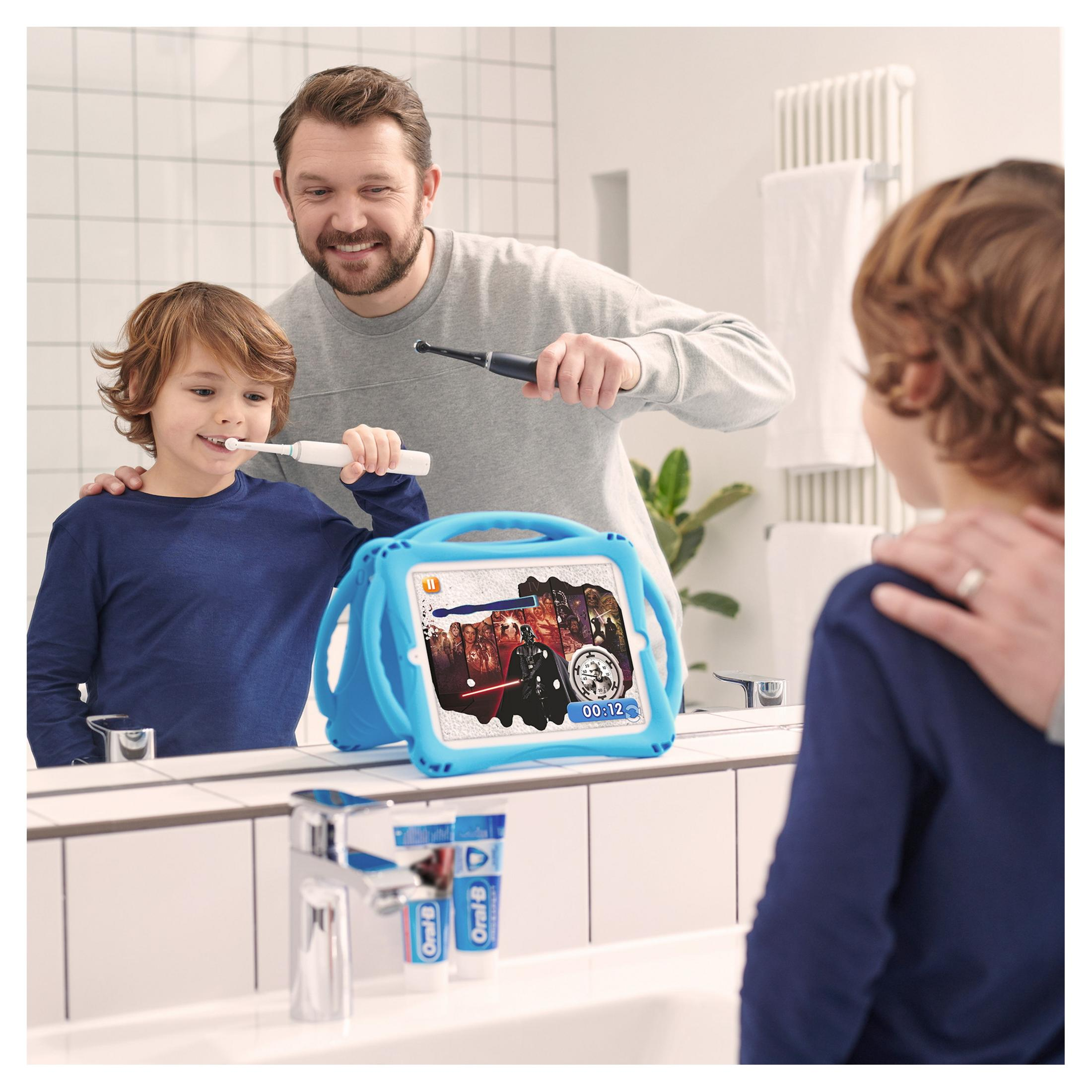 Vater und Sohn putzen sich im Spiegel die Zähne. Blauer Star Wars Tablet.