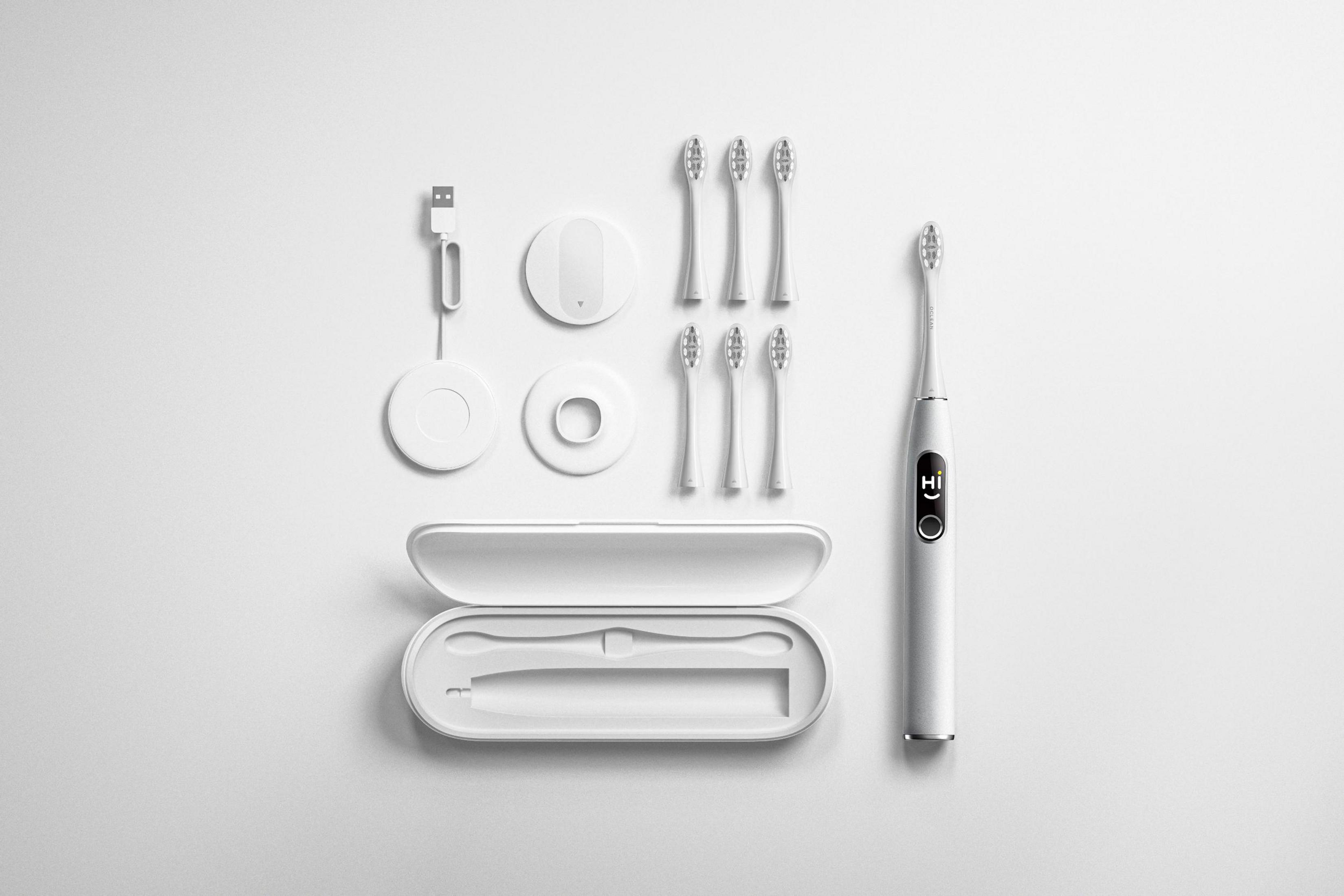 Biały zestaw szczoteczki do zębów. Szczoteczka, głowice, stacja ładująca i etui podróżne są widoczne.