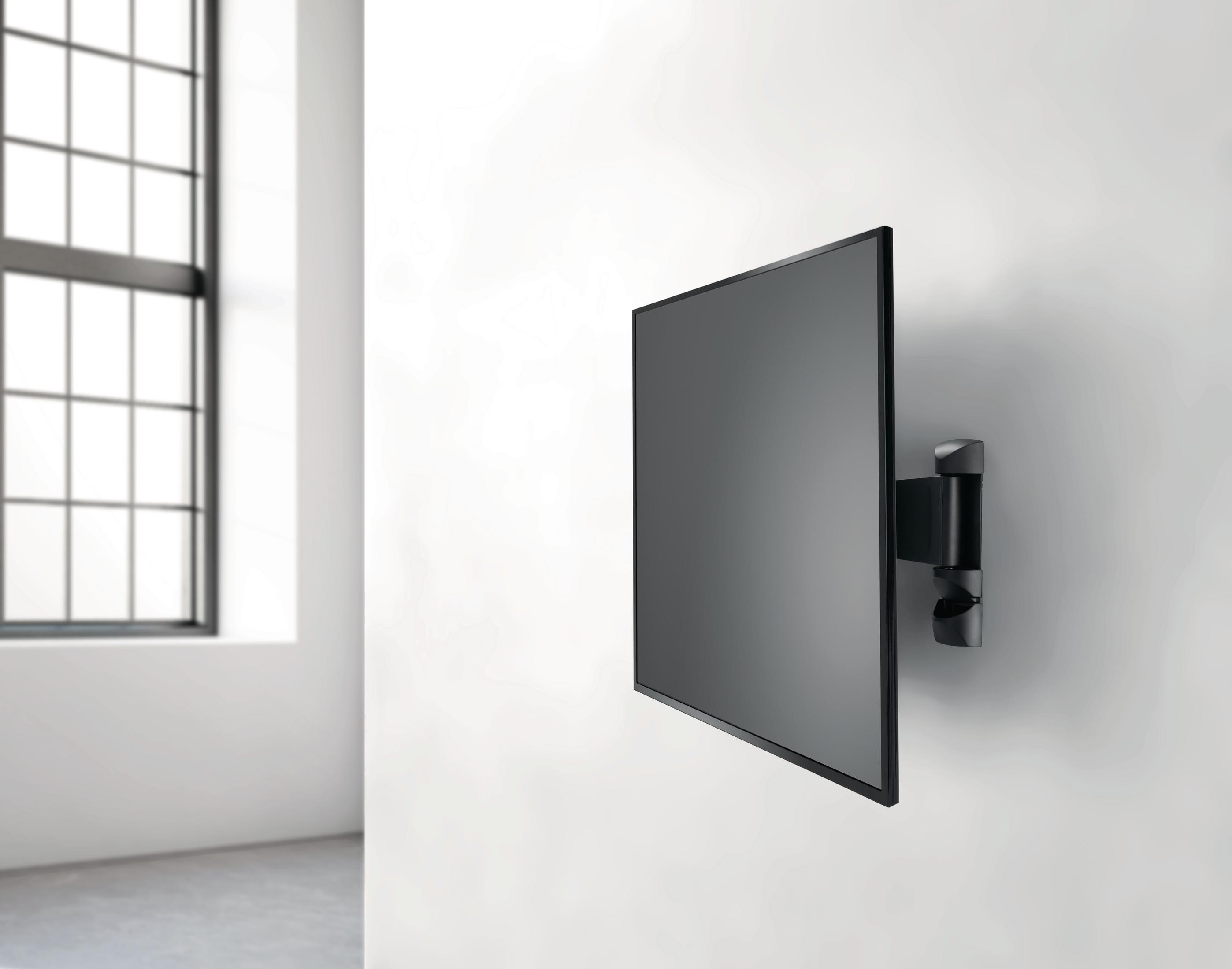 Telewizor zamontowany na białej ścianie z oknem po lewej stronie, z widokiem na zewnątrz.