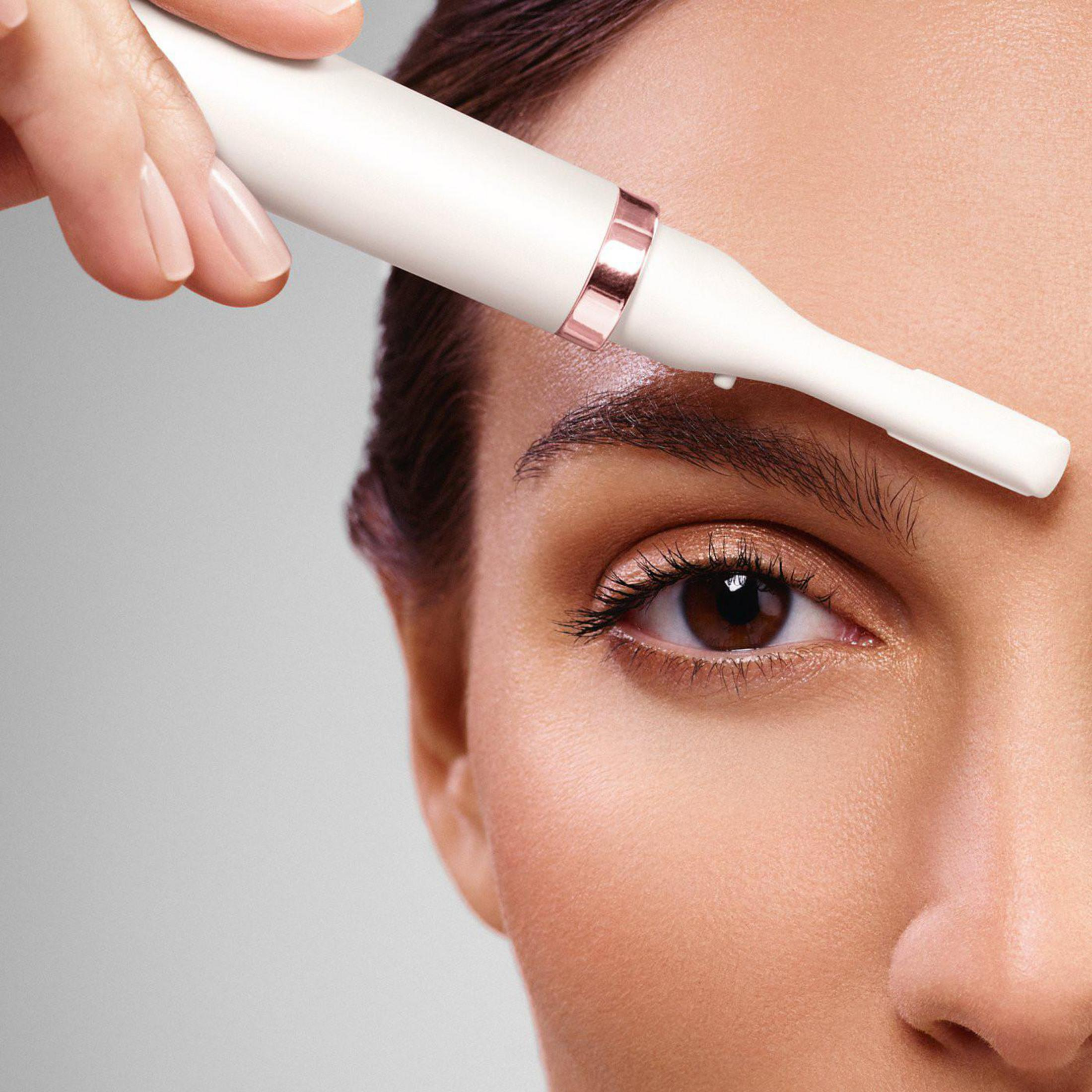 Primer plano del rostro de una mujer con un recortador de cejas. Una mano sostiene el dispositivo.
