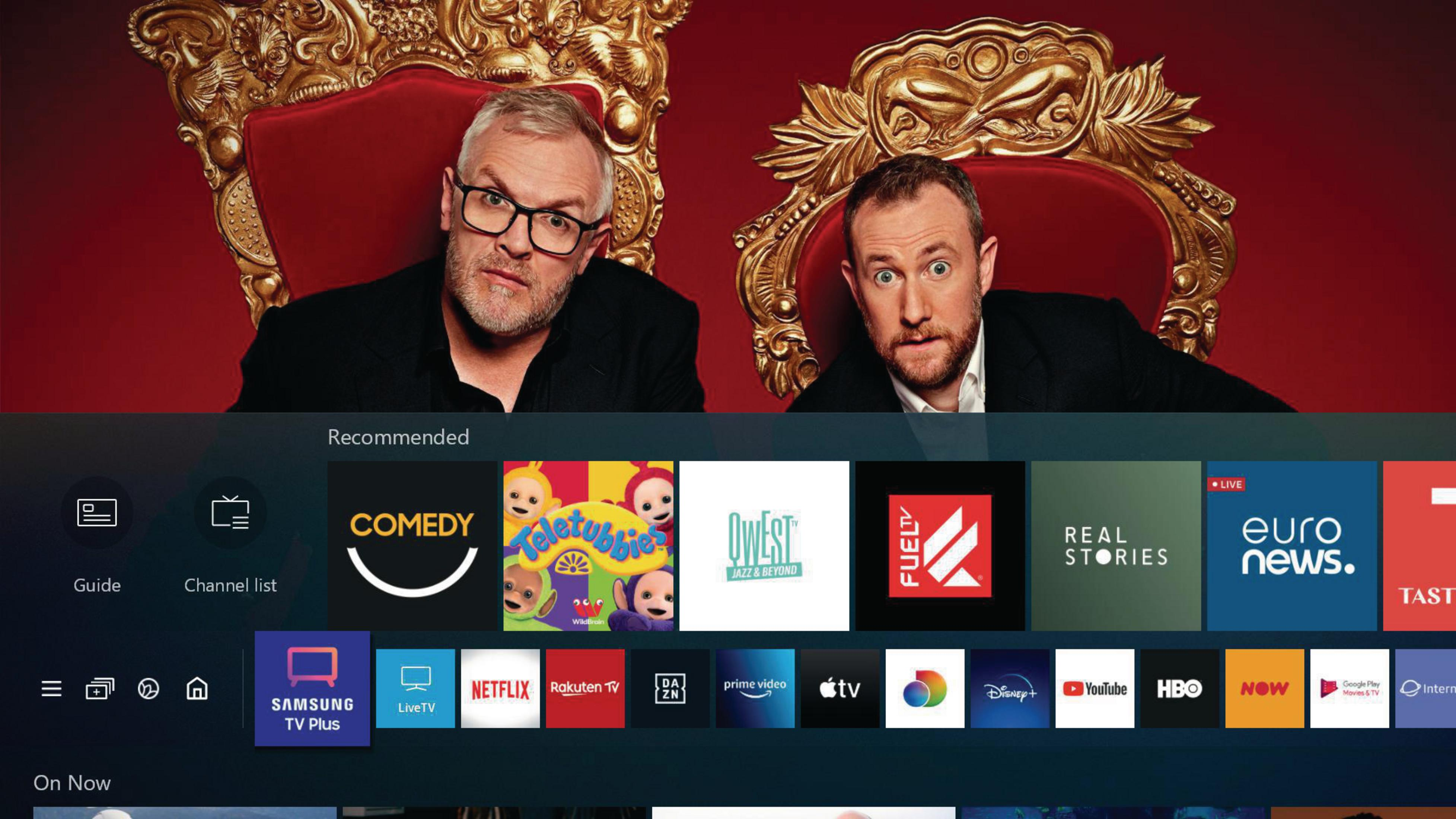 Dwóch mężczyzn siedzi na złotych krzesłach. Telewizor wyświetla interfejs streamingu z ikonami aplikacji.