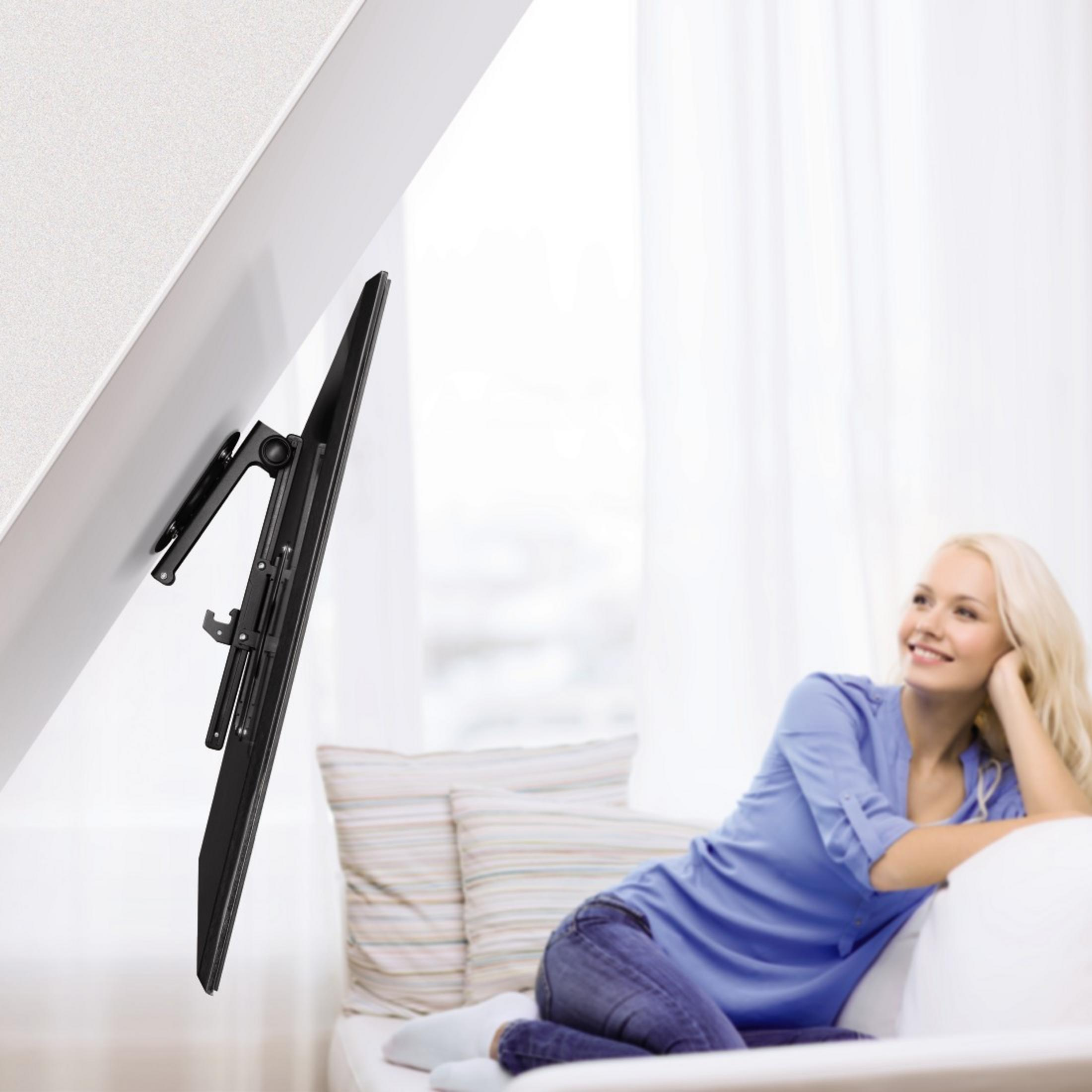 Mujer en un sofá mirando la televisión montada en la pared. La TV está en ángulo.