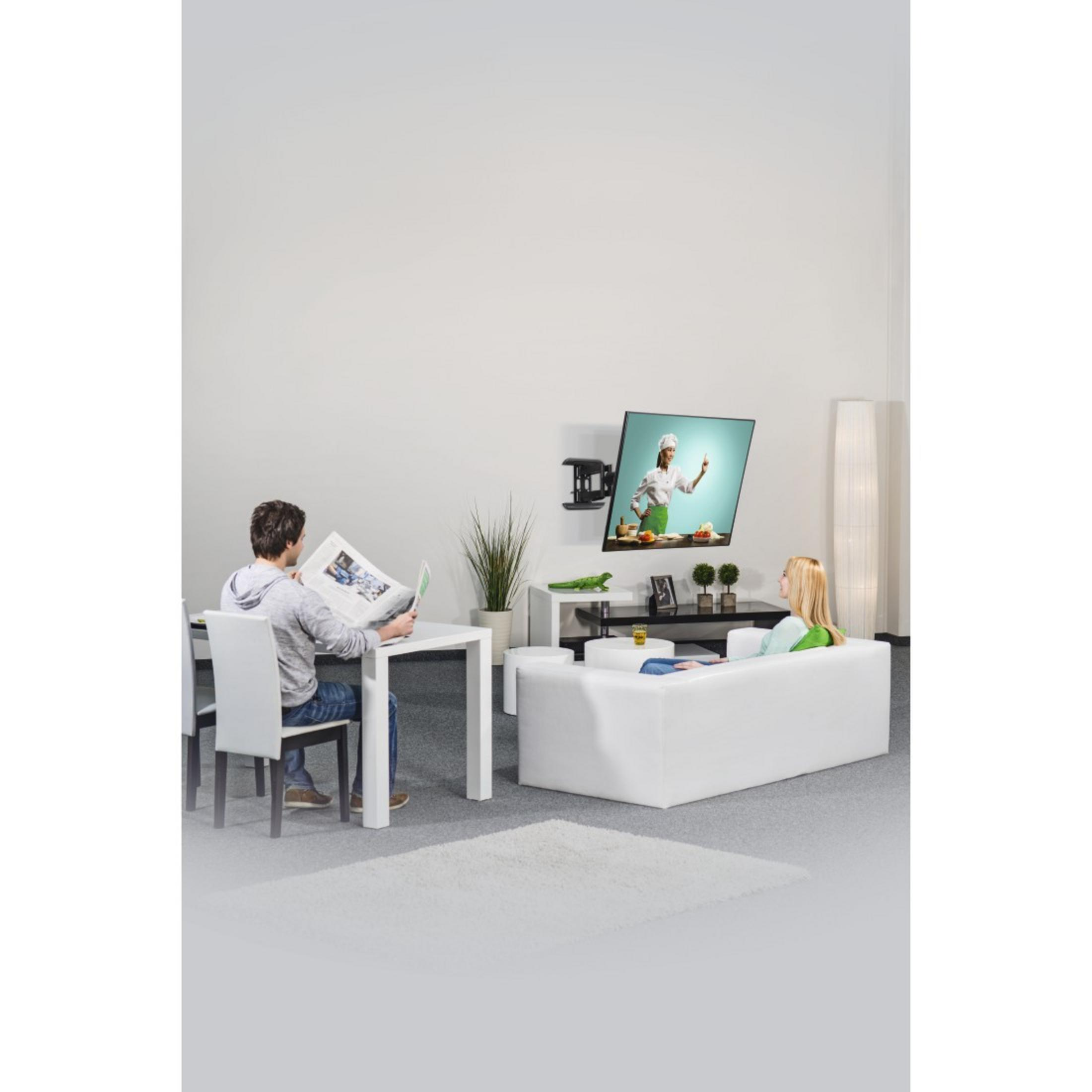 Wohnzimmer mit Wand-TV, zwei Personen, eine liest, eine sieht fern.