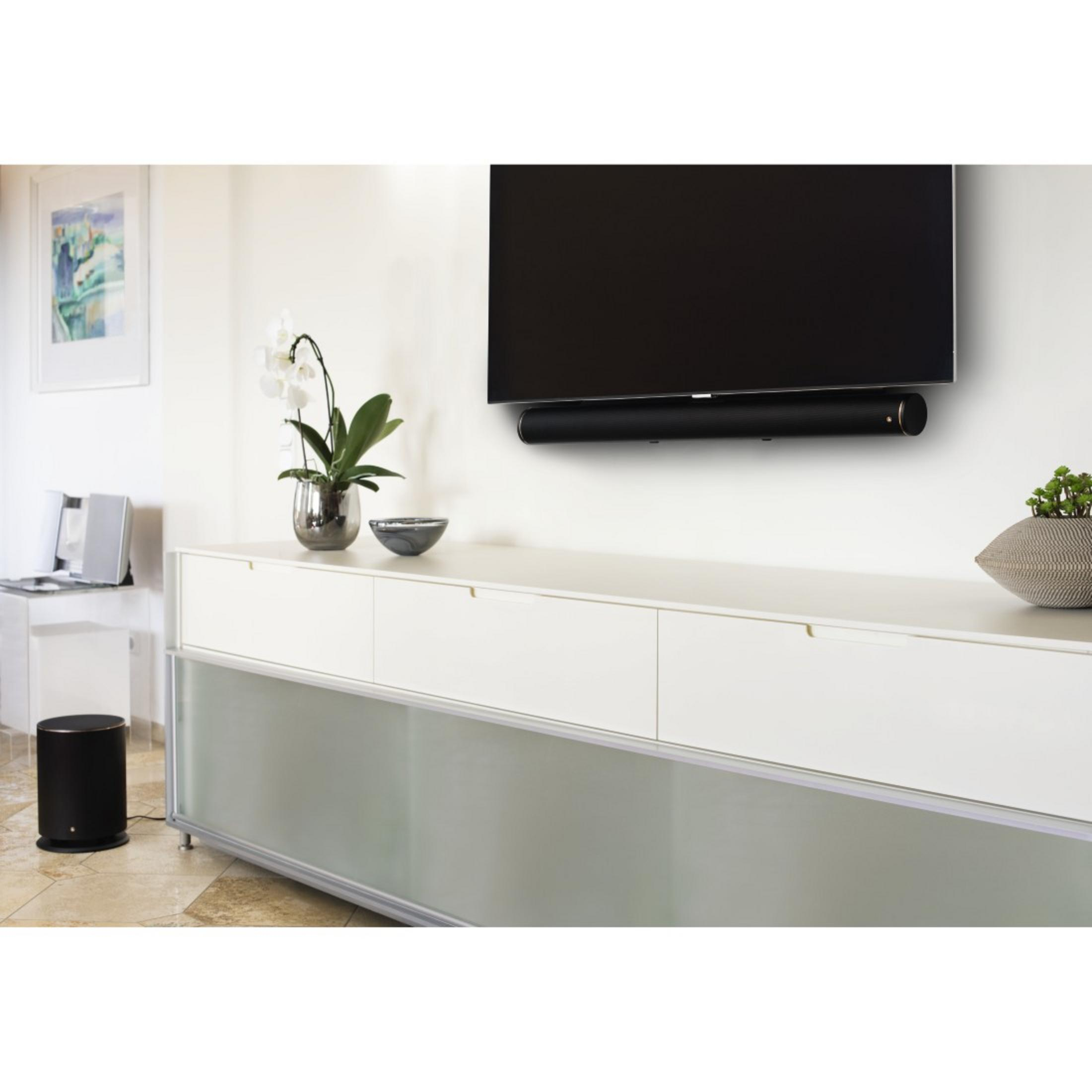 Ein Fernseher an der Wand, darunter eine Soundbar und ein Subwoofer.