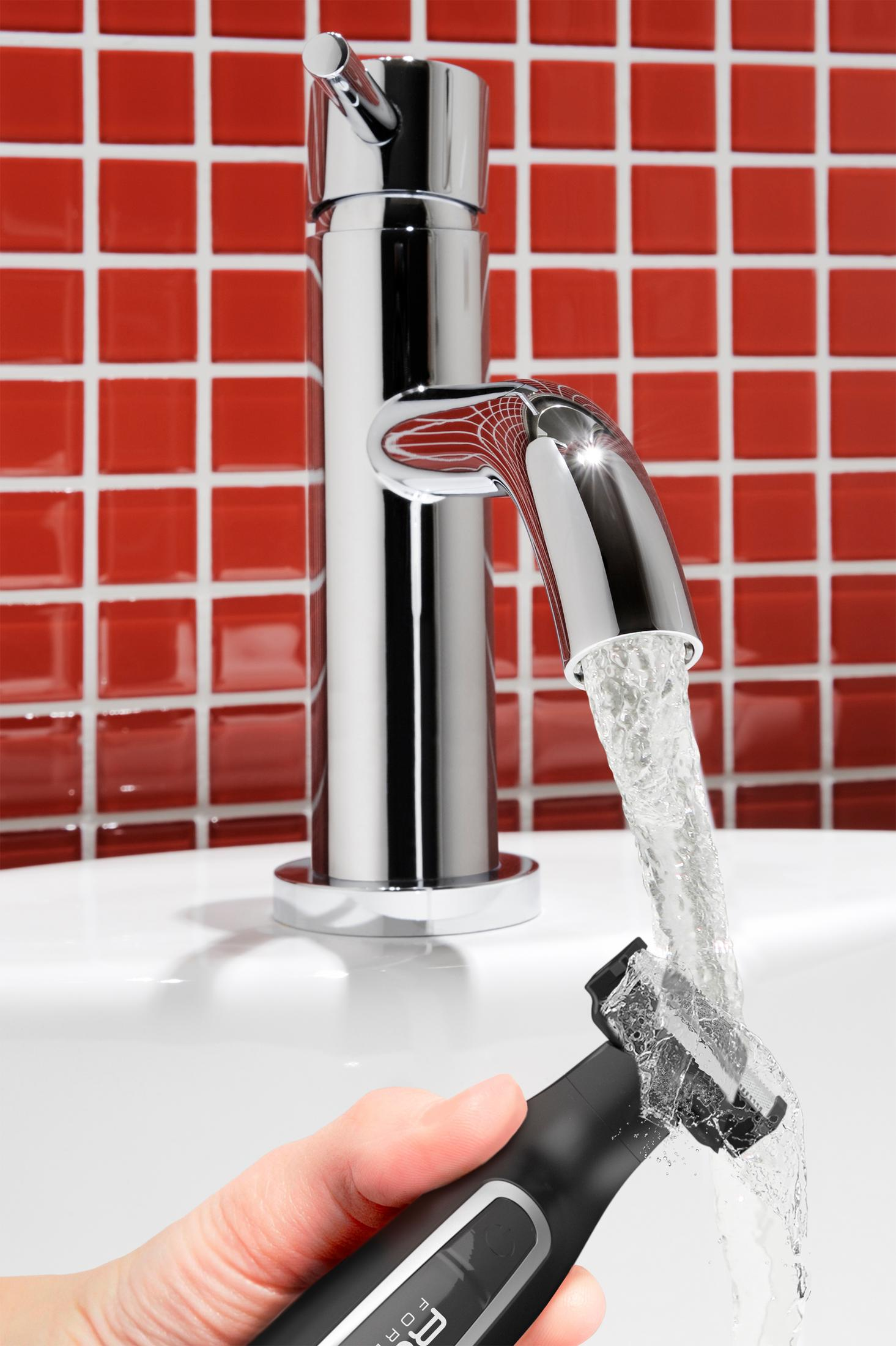 Chromowana bateria z wodą płynącą po czarnej golarce czyszczonej w łazience.