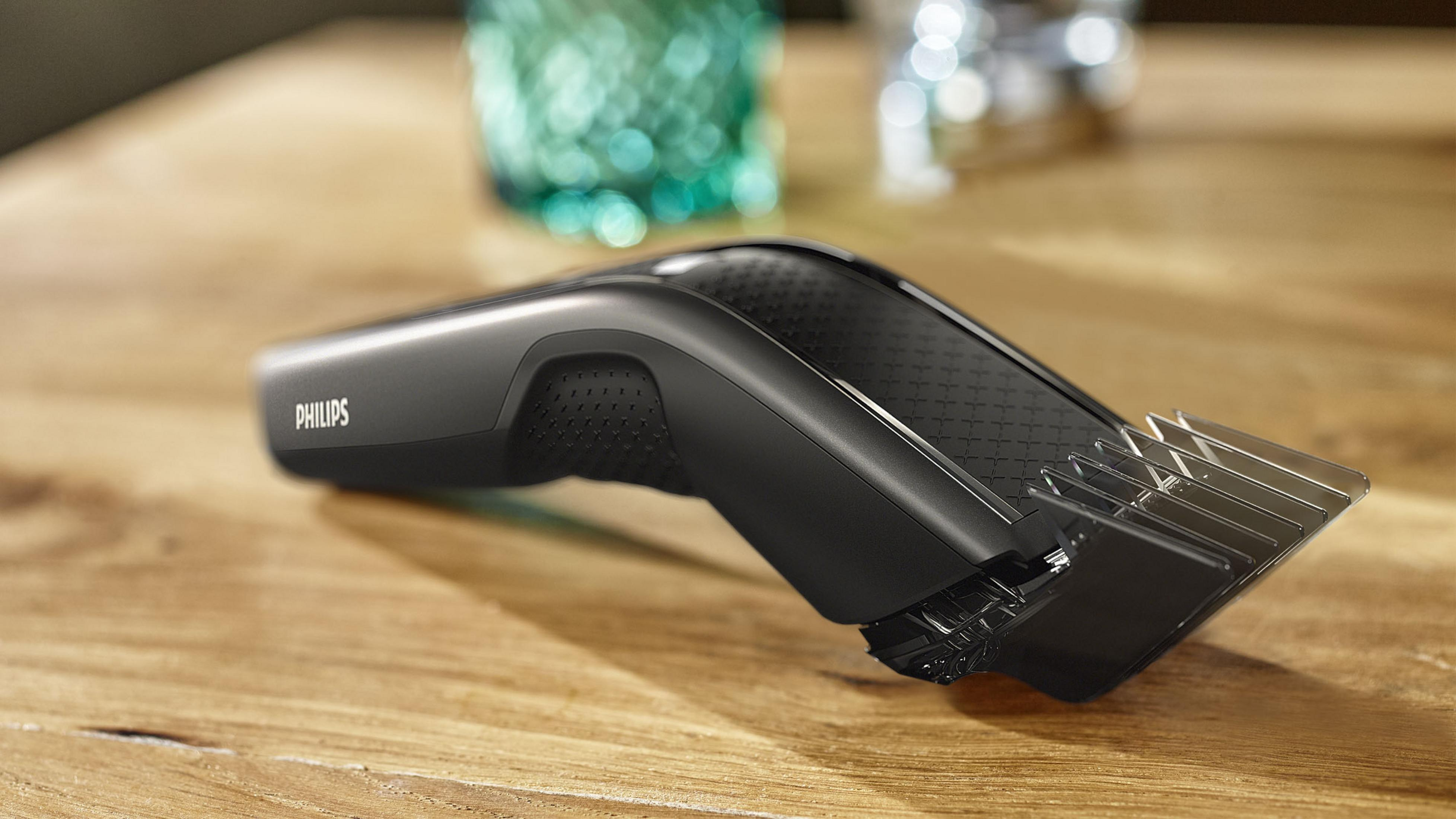 Czarna maszynka do włosów Philips na drewnianej powierzchni, pokazująca ostrze i uchwyt.
