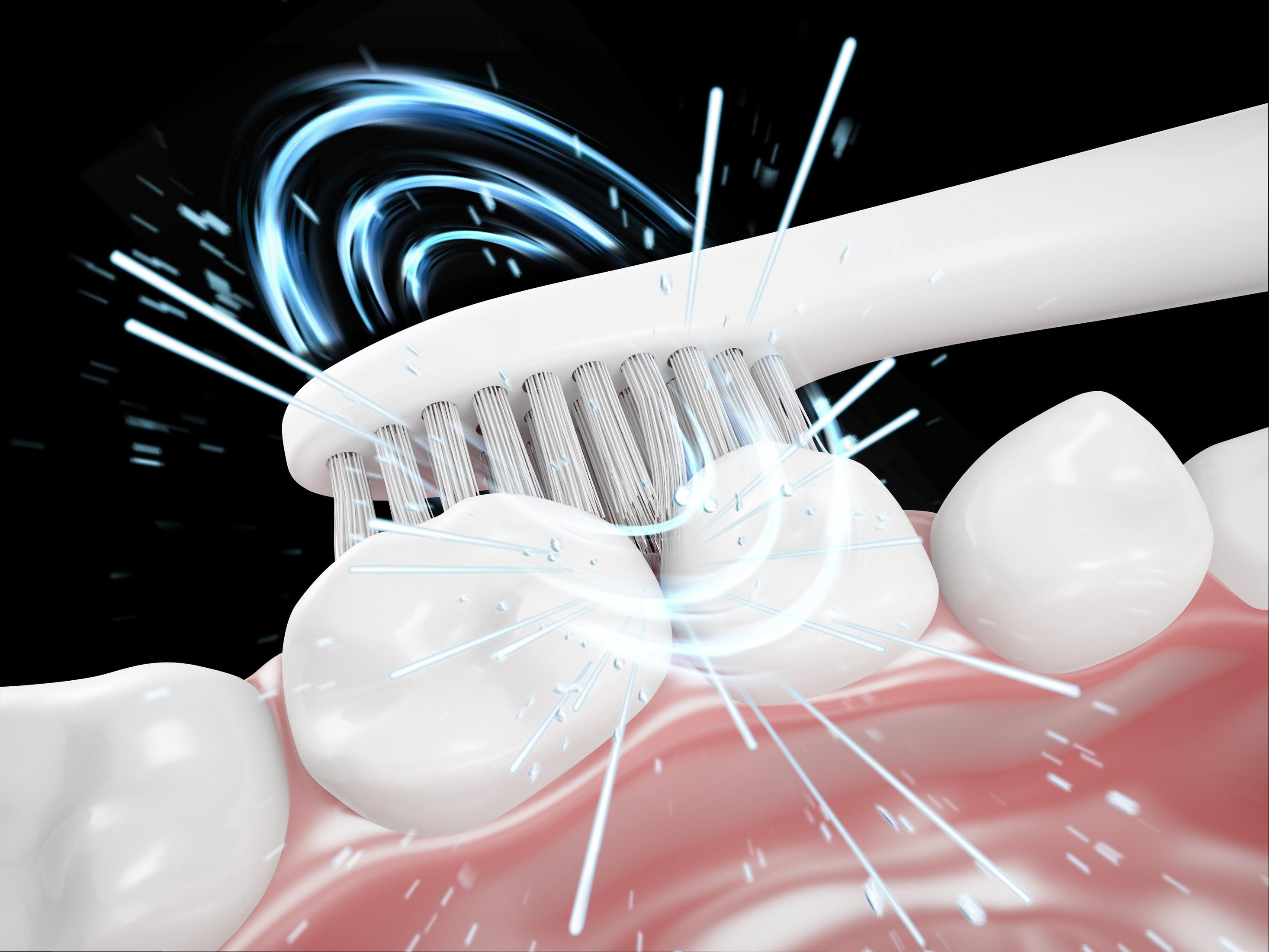 Zbliżenie na zęby czyszczone białą elektryczną szczoteczką. Niebieska energia wiruje wokół włosia.