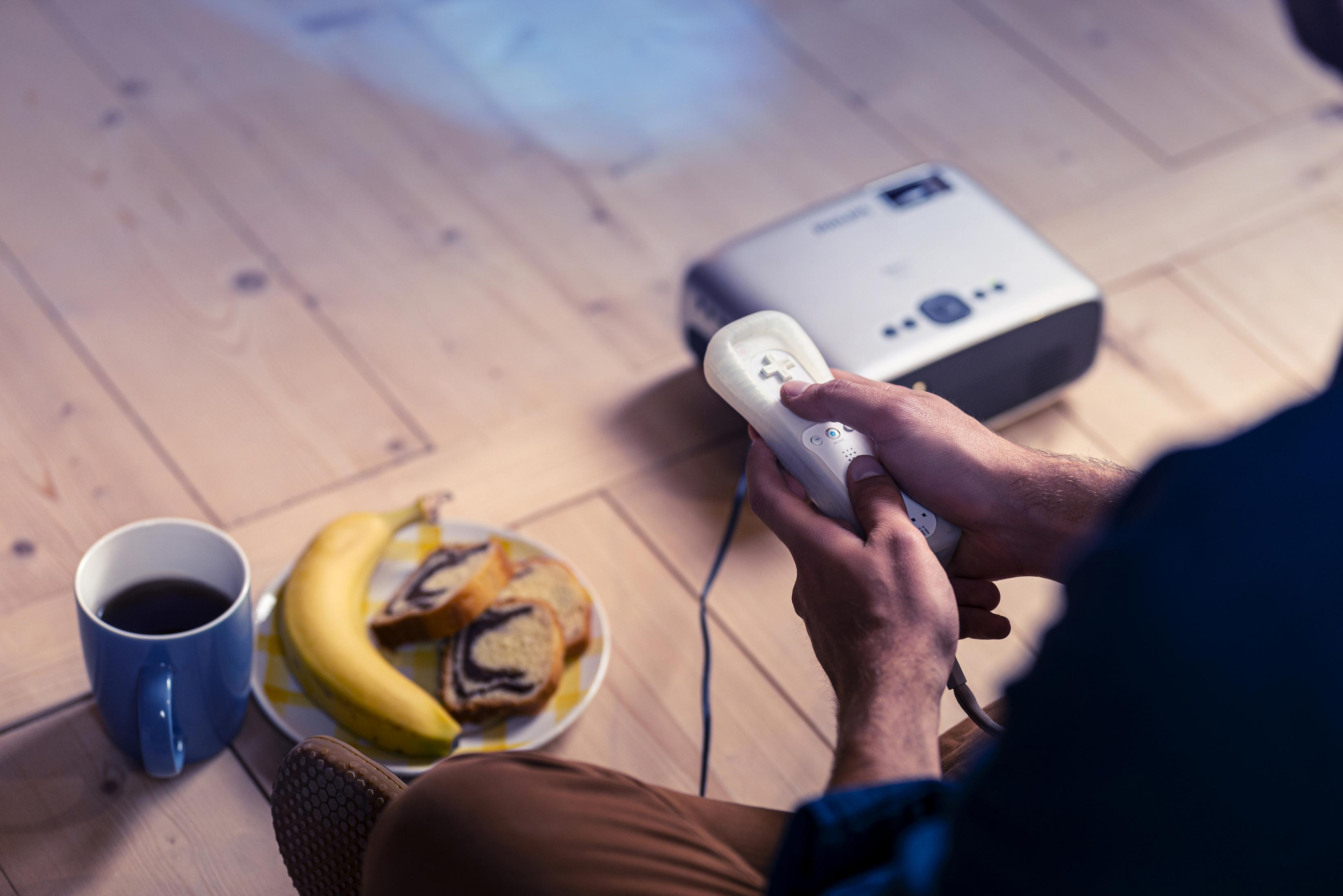 Osoba trzyma pilota, oglądając film na projektorze.