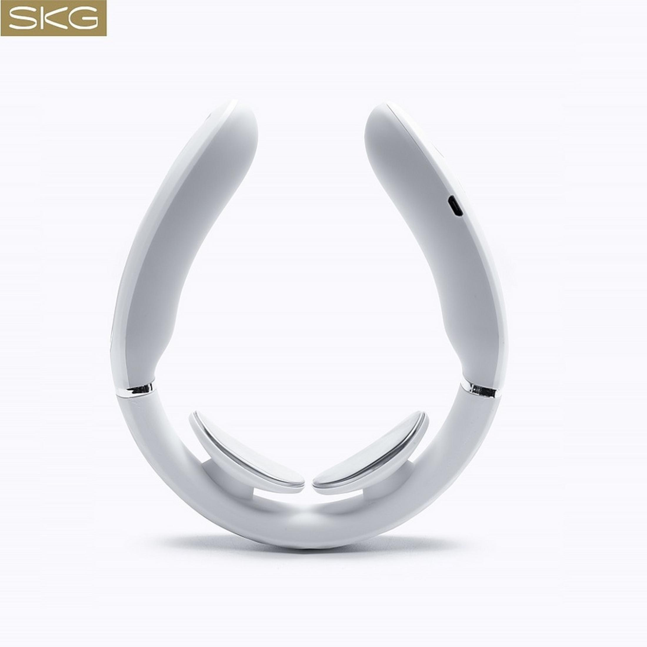 Un massaggiatore per il collo bianco, a forma di U, giace su una superficie bianca. Il logo SKG è visibile.