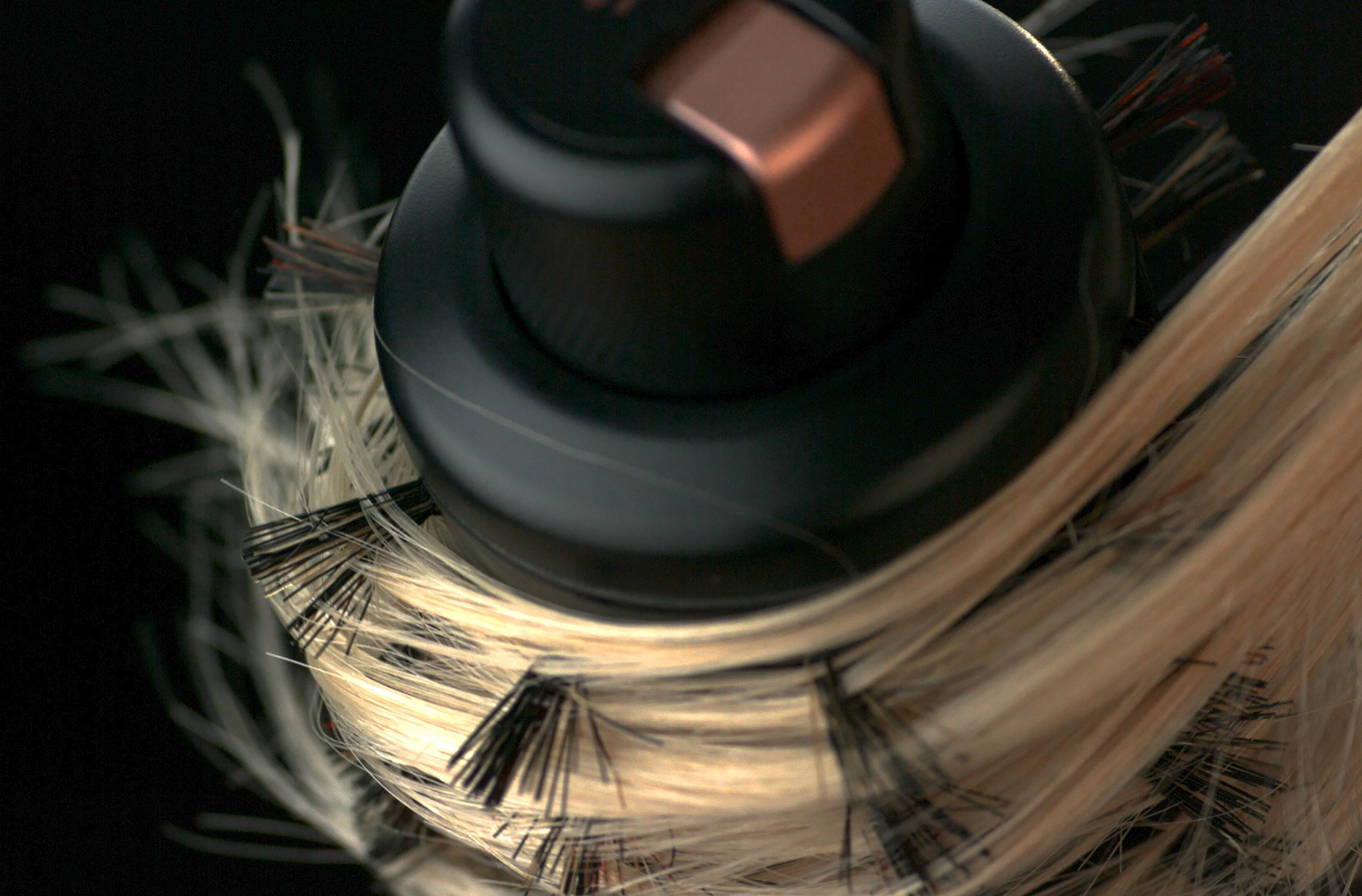 Zbliżenie szczotki do włosów z owiniętymi włosami na czarnym tle.