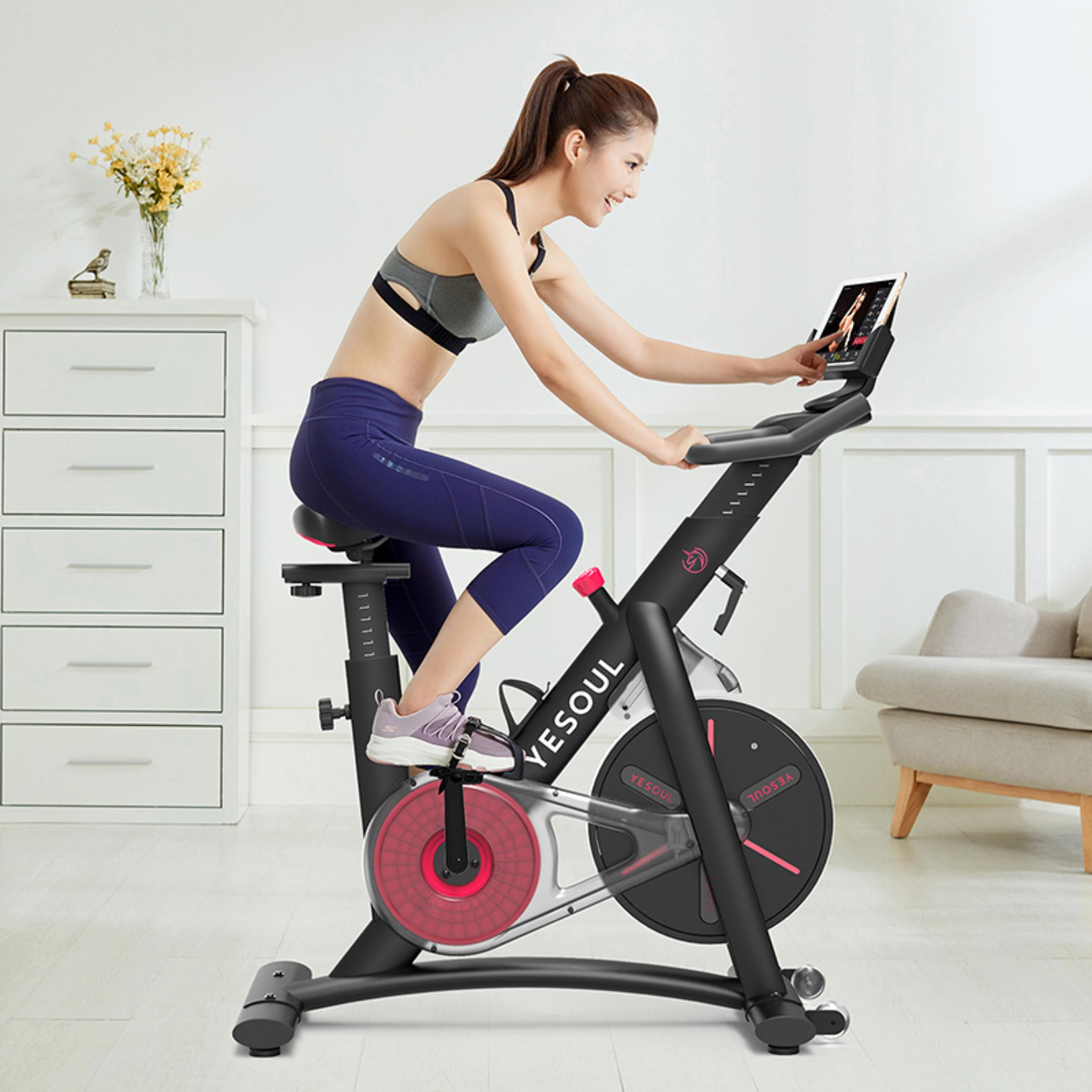 Una donna che fa cyclette e usa un tablet.